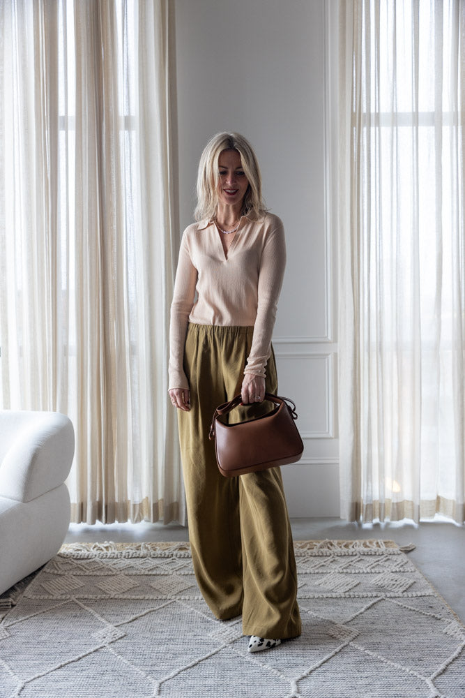 image of a woman wearing the Alysi Maglia Polo and Wide Leg Pull on Trouses with the Aesther Ekme Soft Baguette Bag