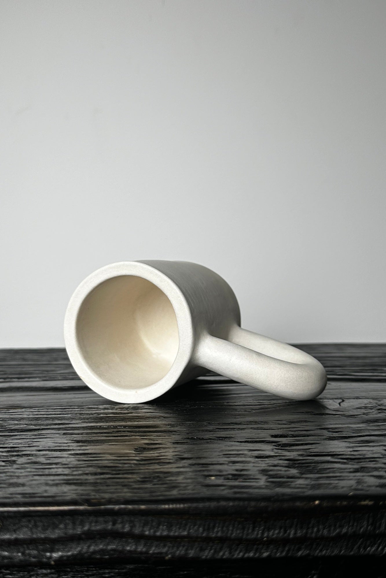 Ceramic cup with a handle on a dark wooden surface against a gray background