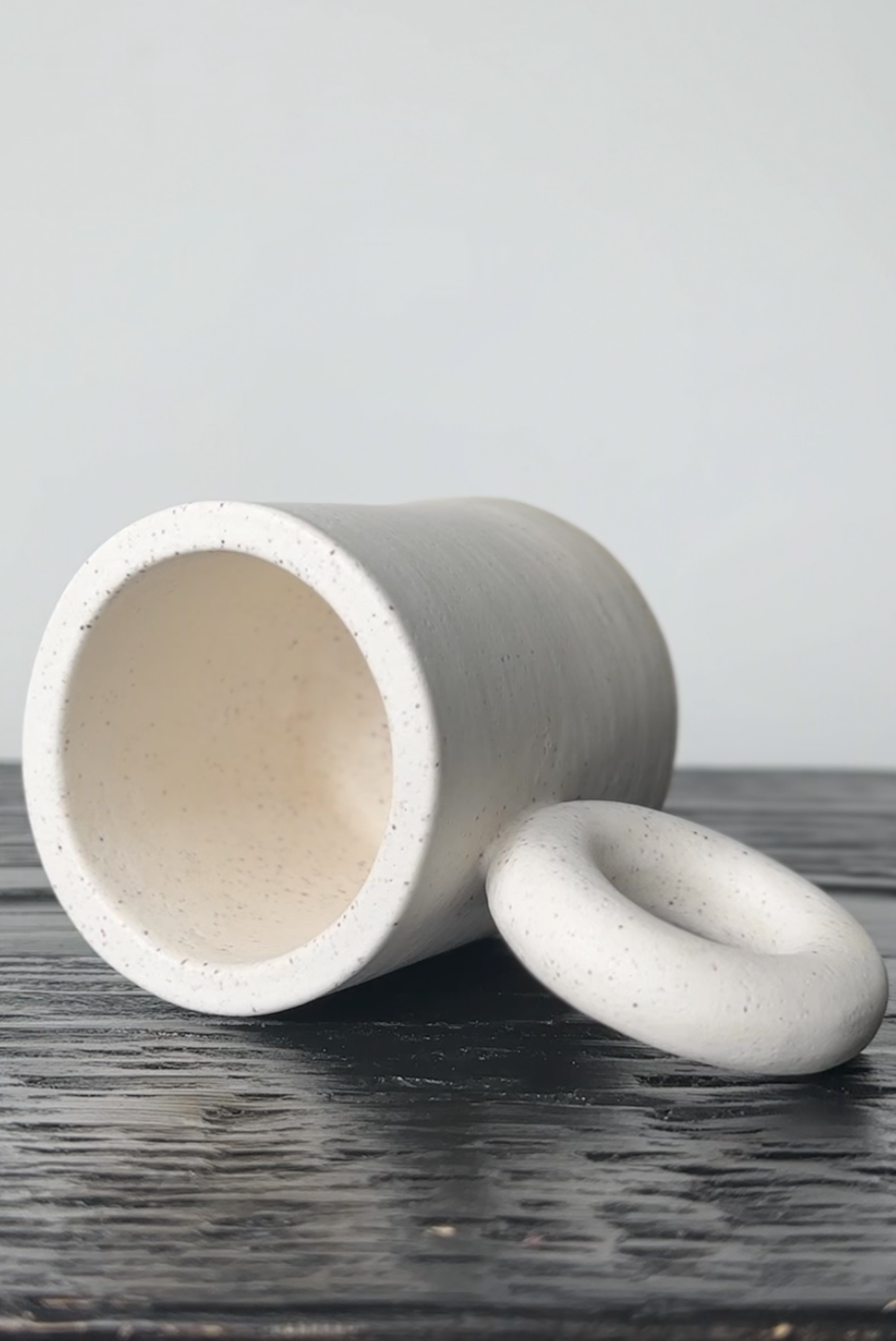 Concrete cylindrical object with a smaller circular piece on a wooden surface