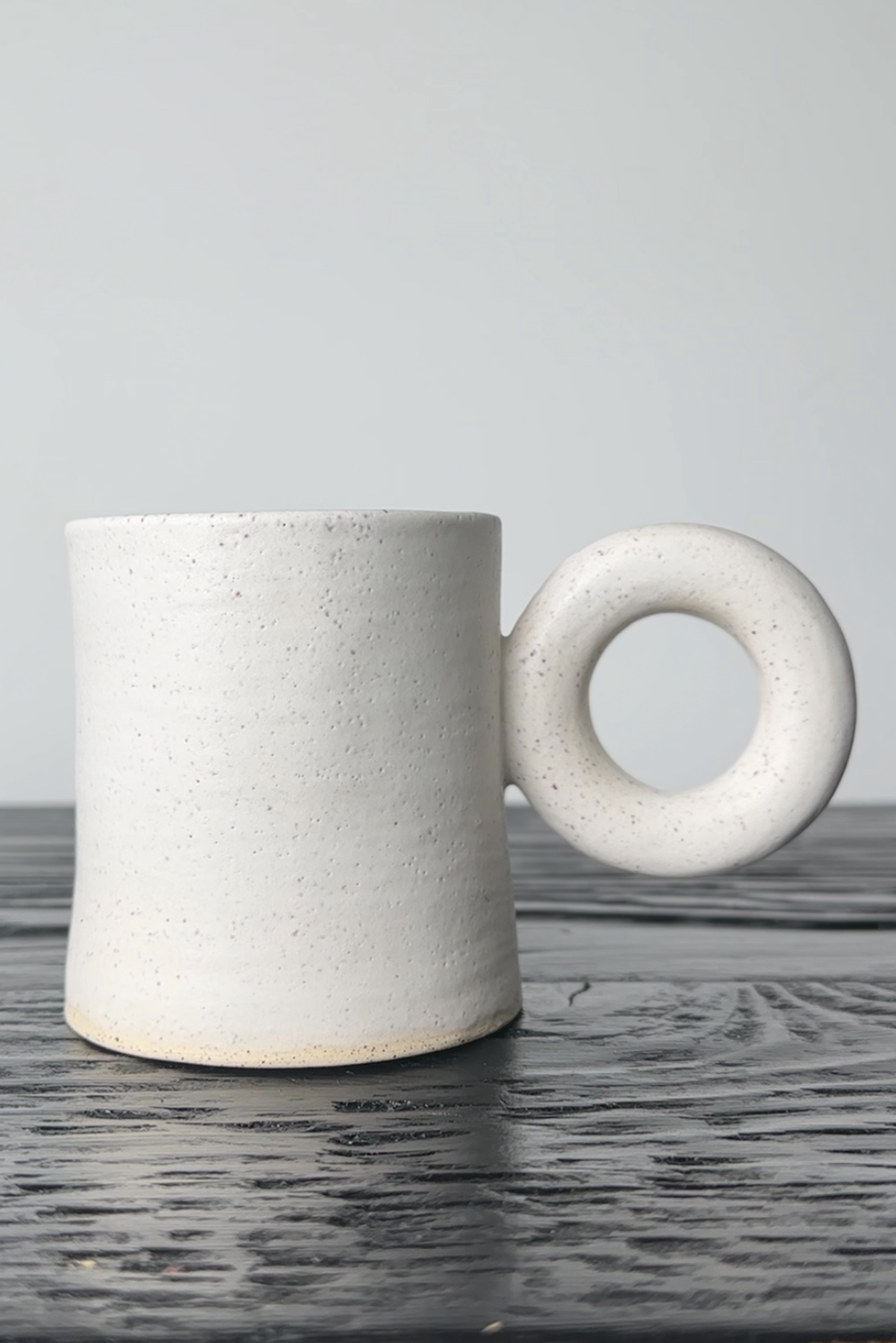 White ceramic mug with a unique handle on a wooden surface