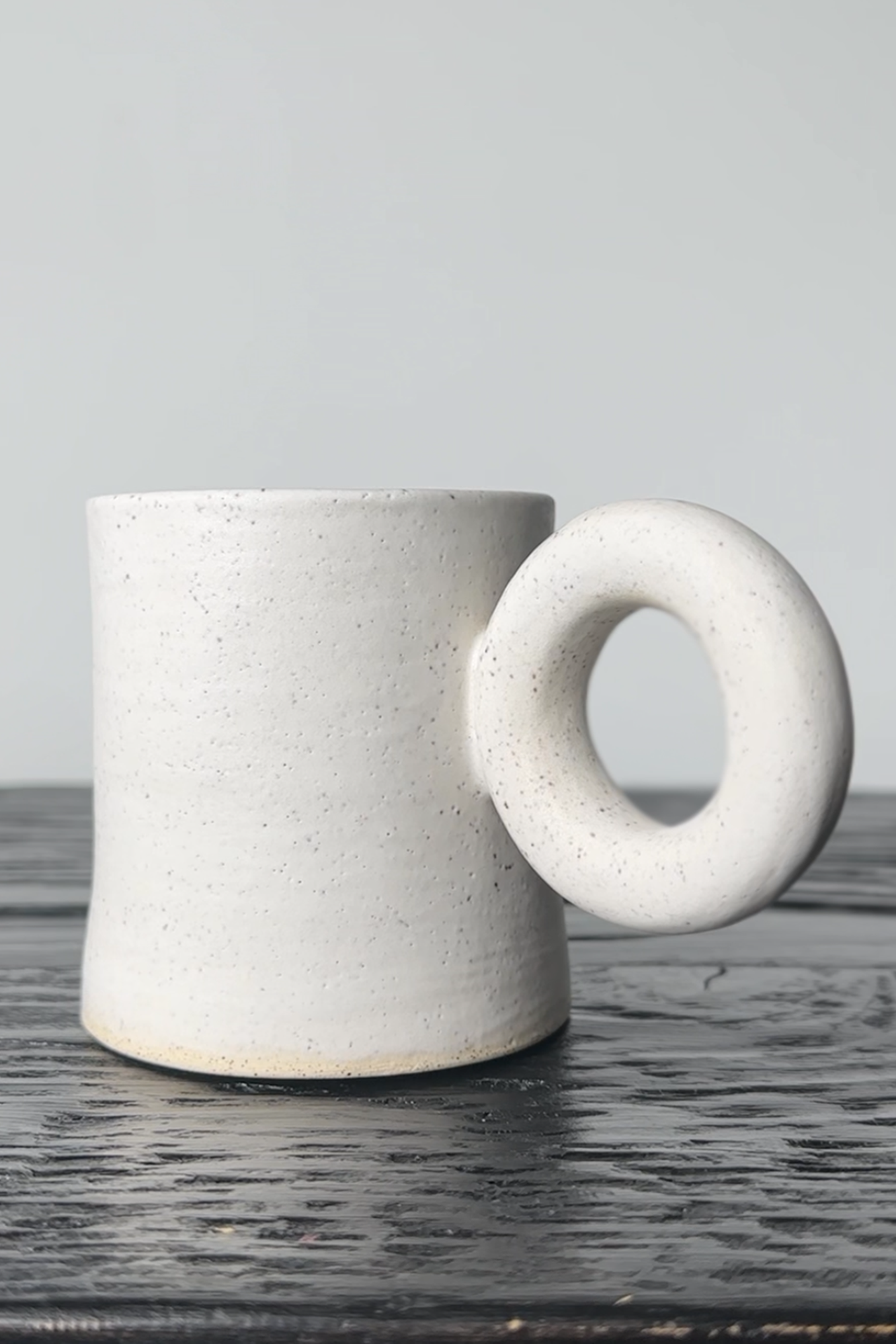 White ceramic mug with unique handle on a wooden surface