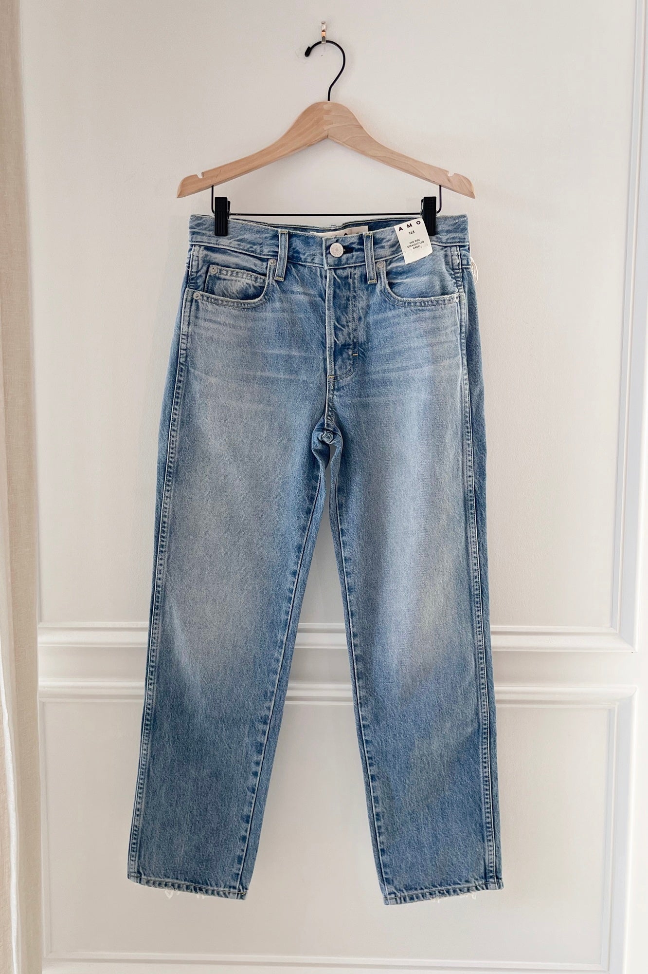 Image of amo 143 jeans hanging in front of a white wall