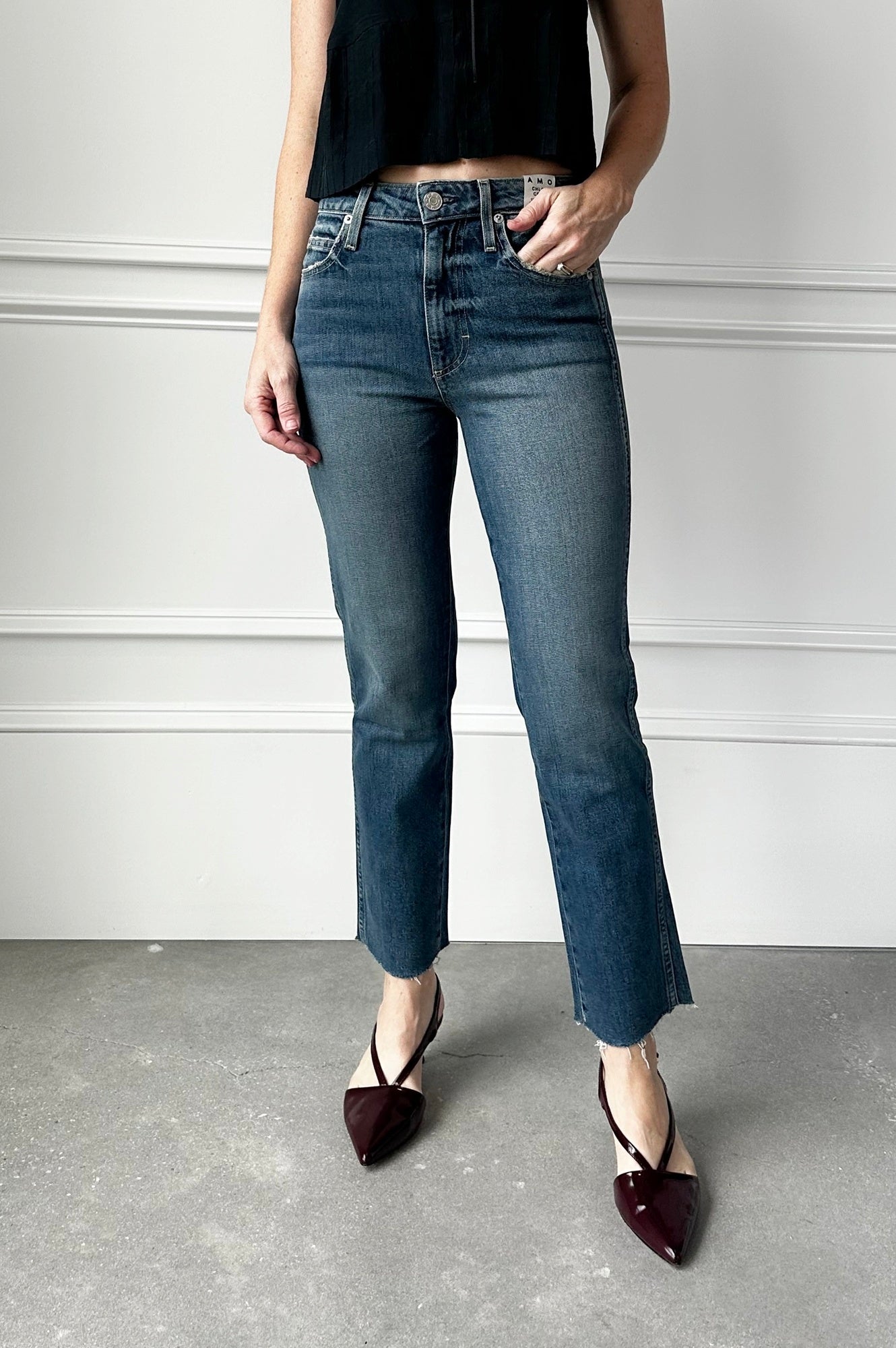Person wearing blue jeans and black shoes on a plain background