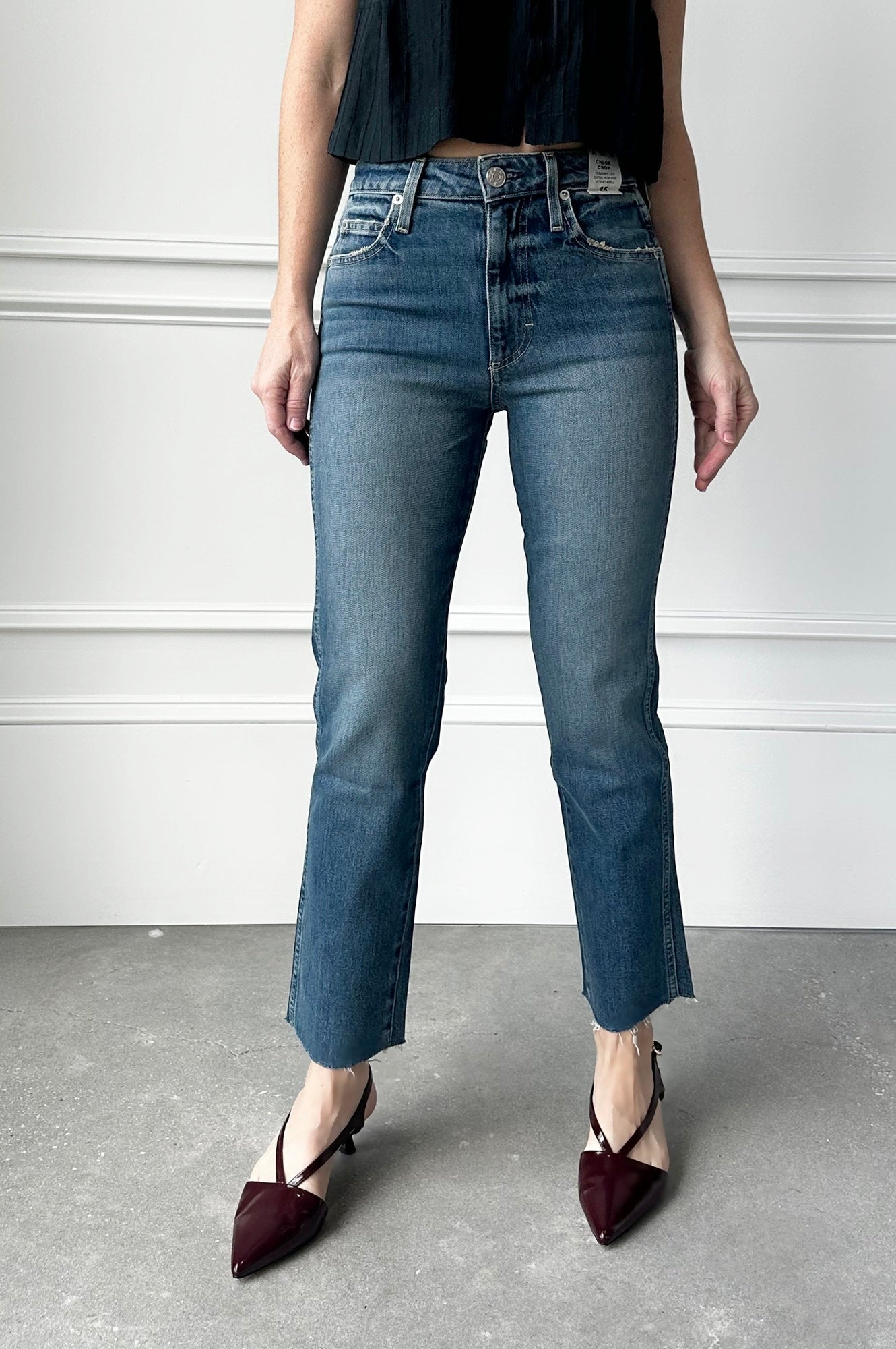 Person wearing blue jeans and black shoes on a plain background