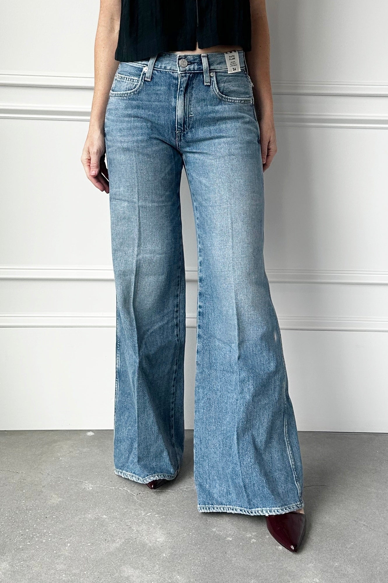Person wearing blue flared jeans against a white wall.