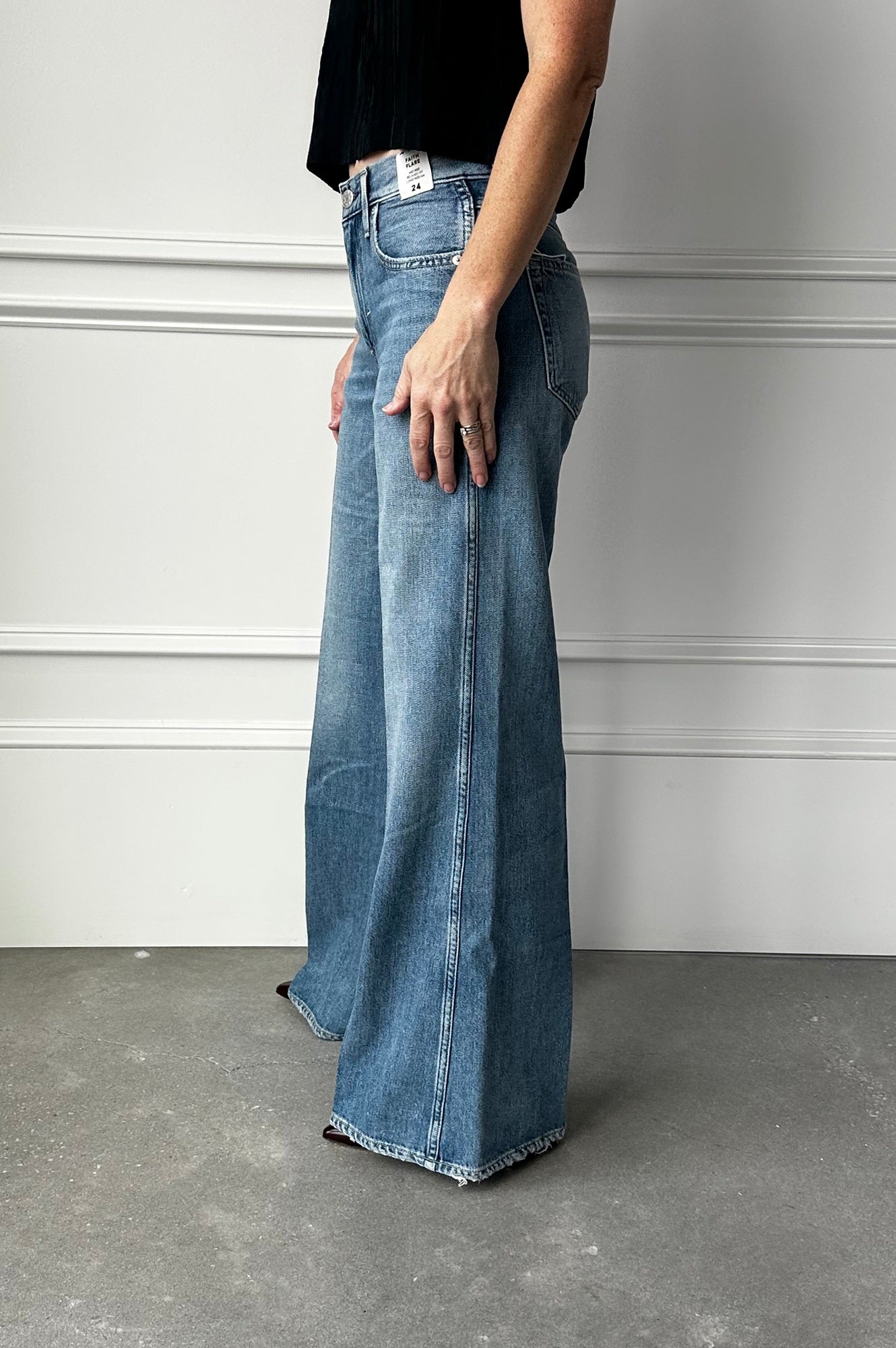 Person wearing blue jeans against a plain wall.