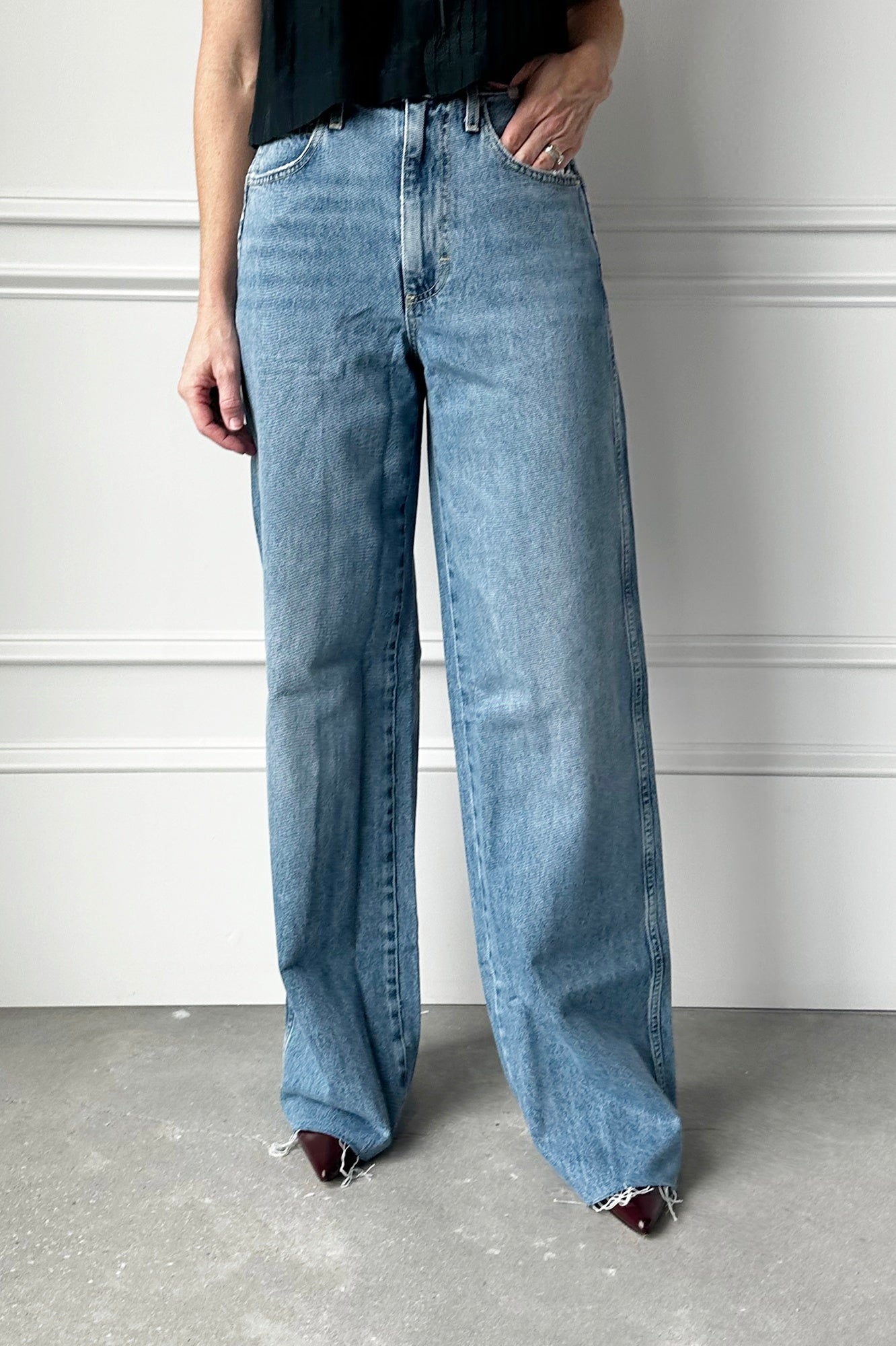Person wearing light blue jeans standing against a plain background