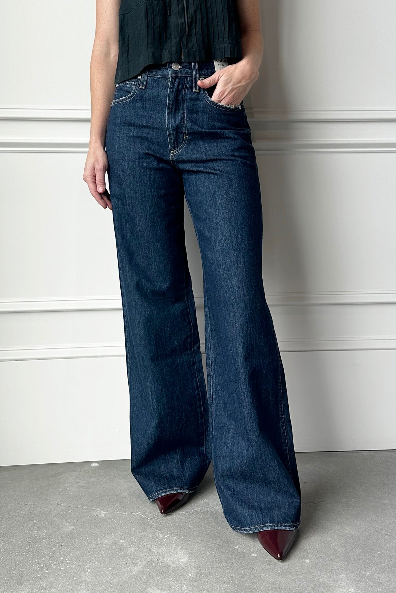 Person wearing blue wide-leg jeans against a white wall.