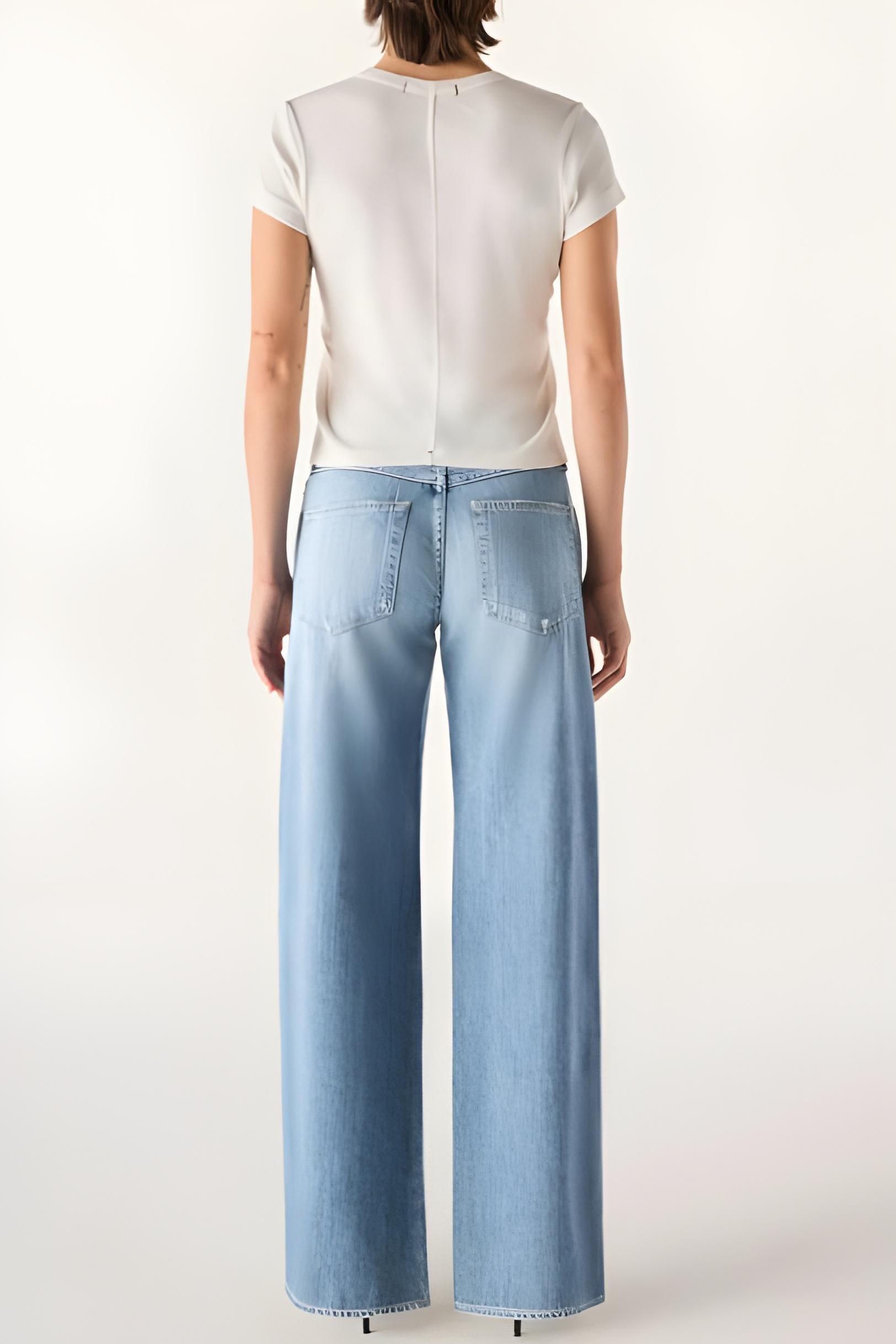 Person wearing light blue jeans and a white top on a white background