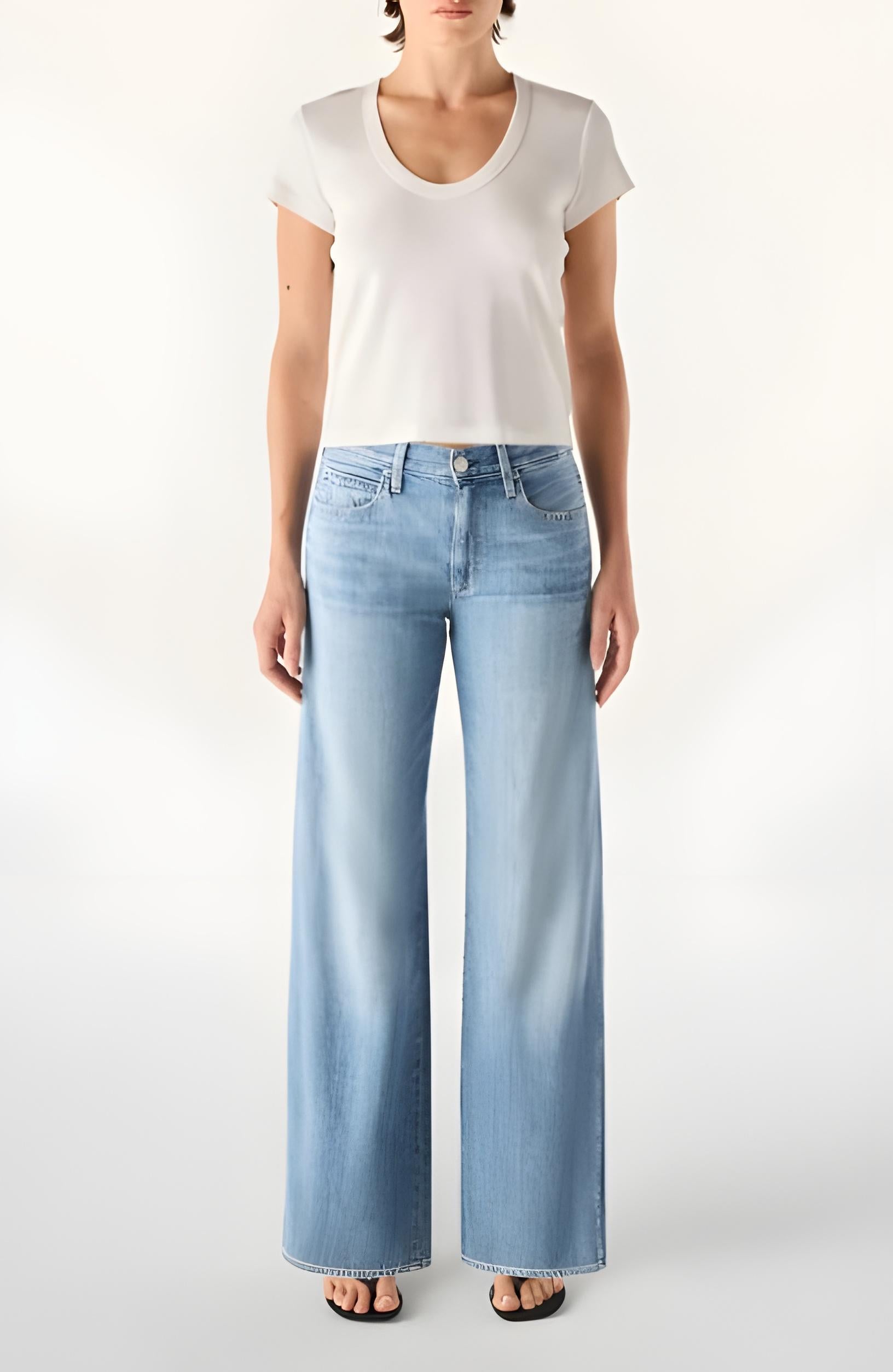 Person wearing a white t-shirt and light blue jeans on a white background