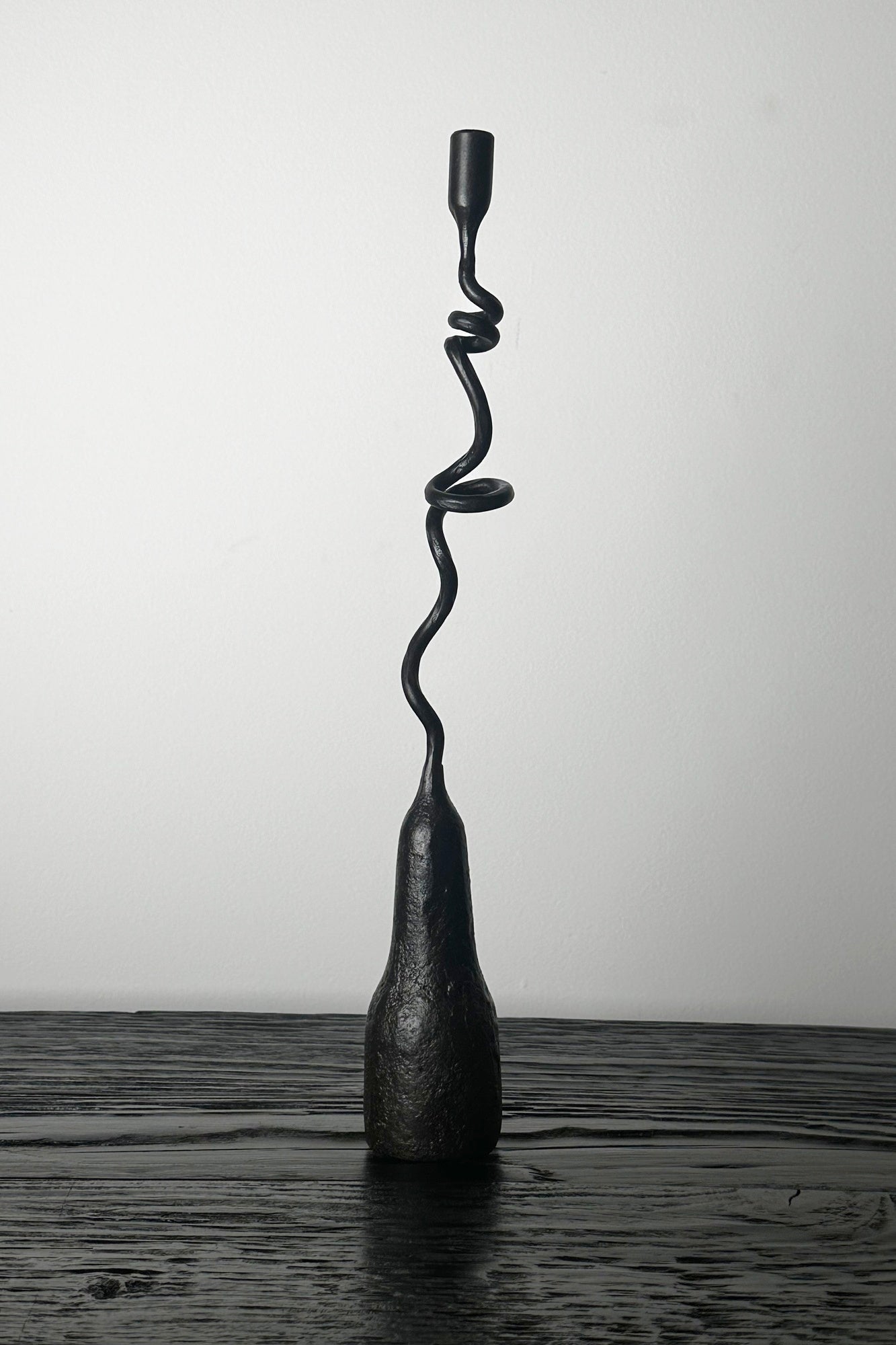 Black spiral lamp on a wooden surface with a white background