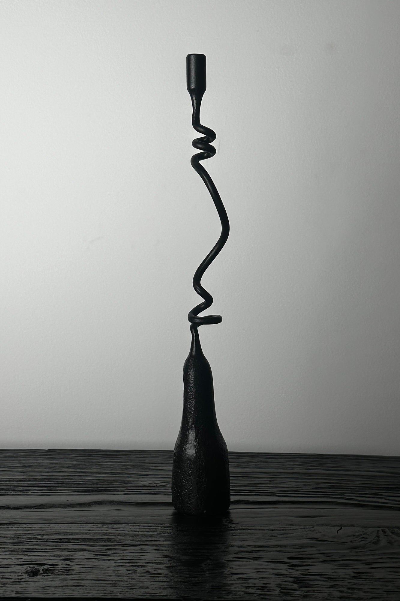 Black spiral lamp on a wooden surface with a white background