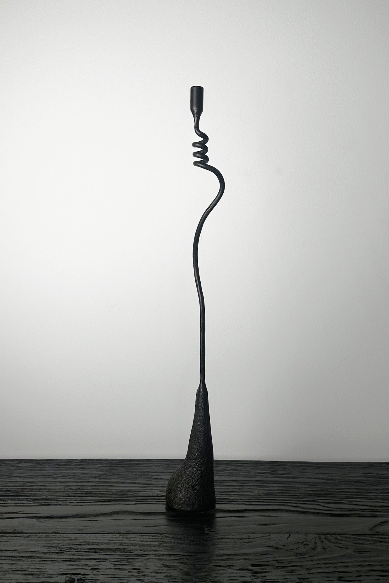 Black metal sculpture on a wooden surface with a plain background
