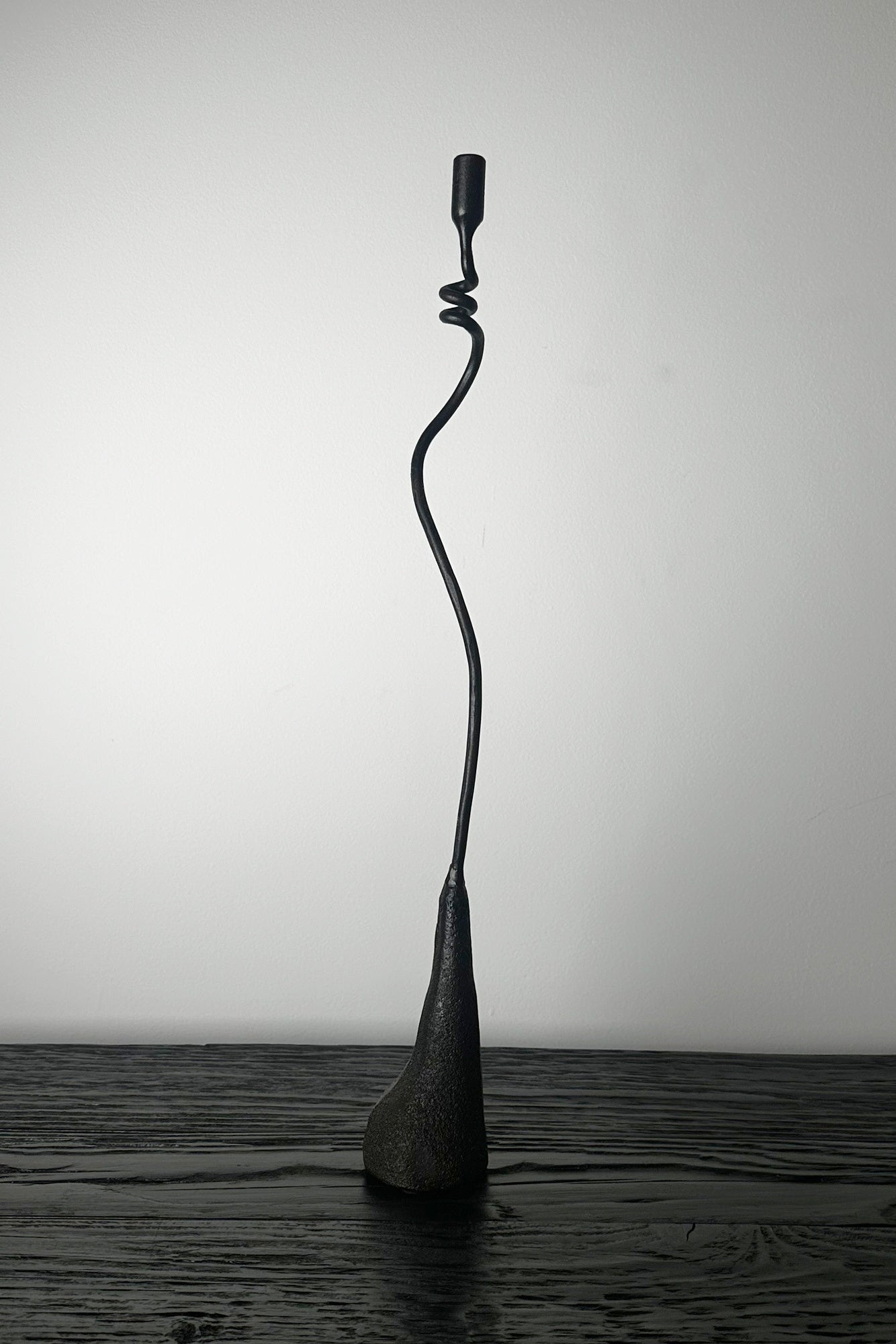 Black abstract sculpture on a wooden surface with a plain background