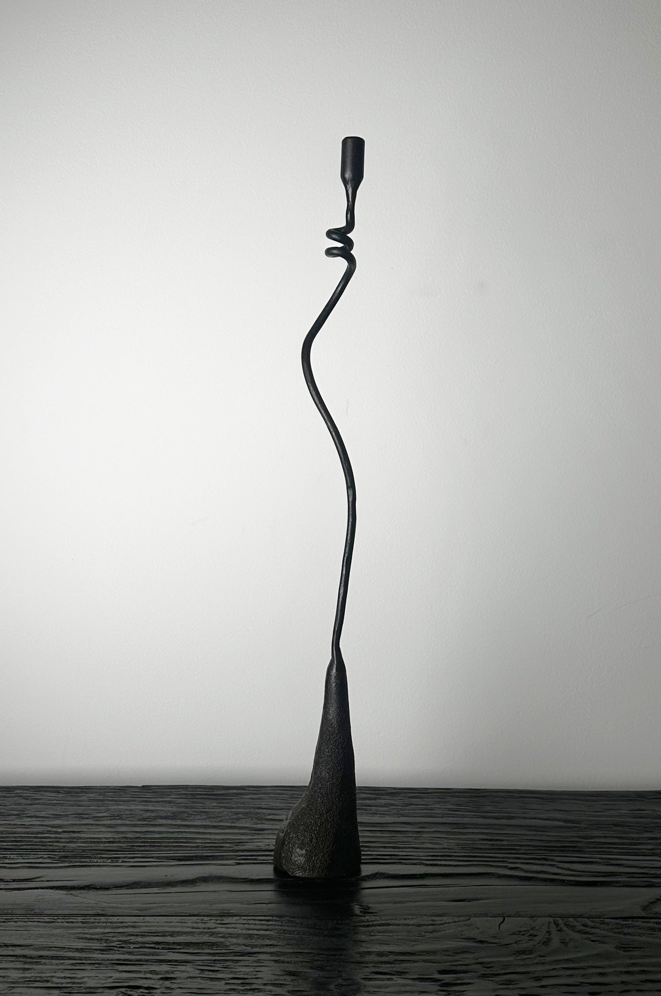 Black abstract sculpture on a wooden surface with a white background