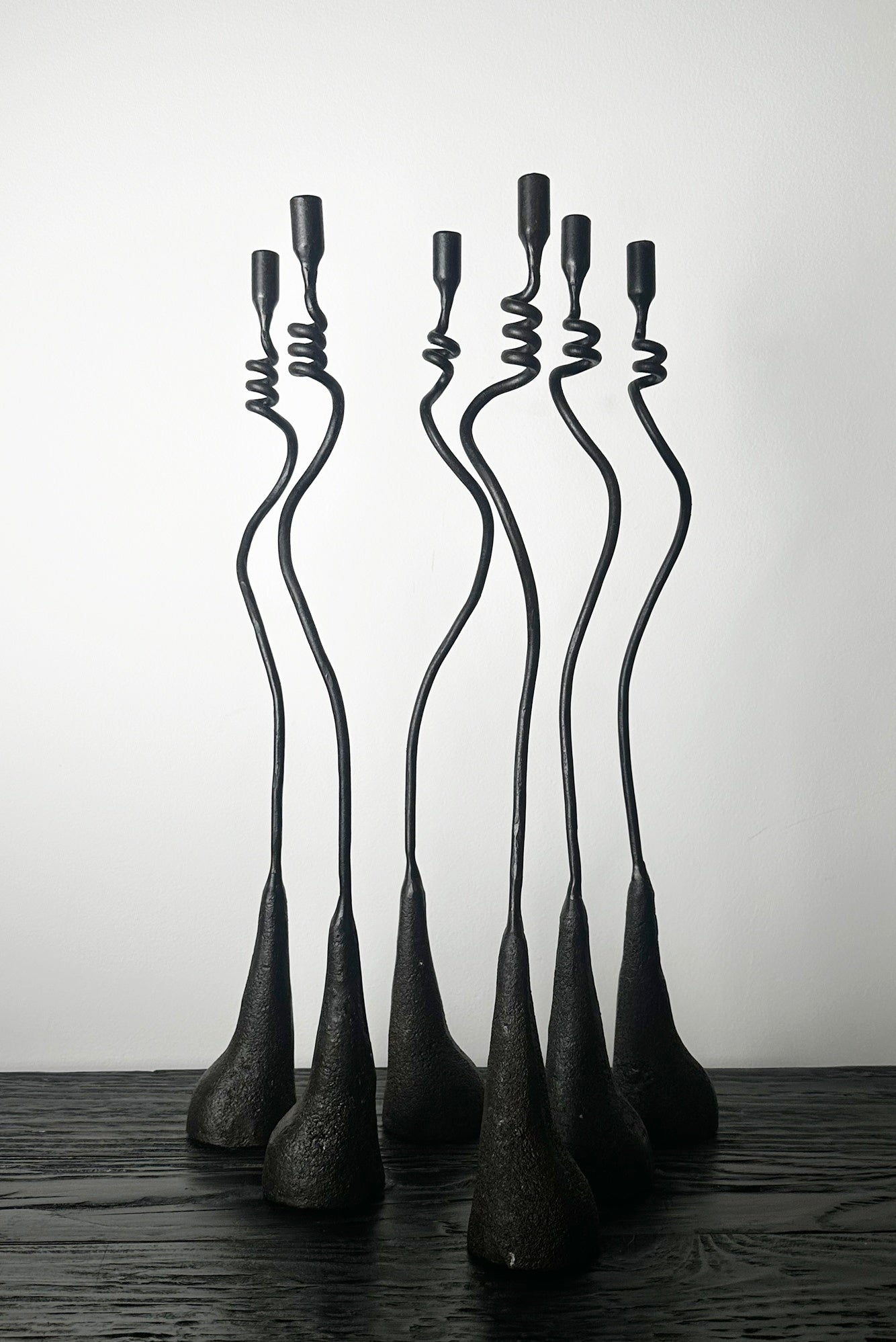 Set of five black metal sculptures on a wooden surface with a white background