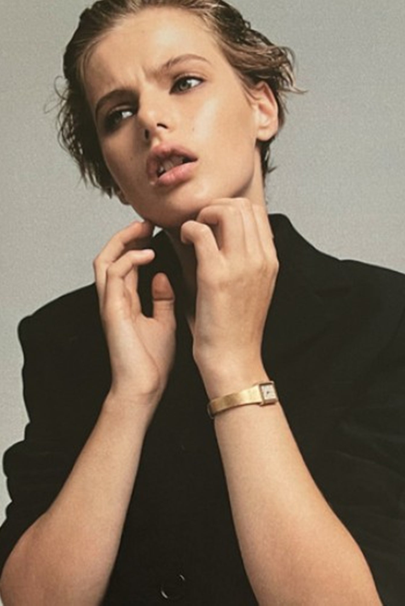 Woman wearing a gold bracelet with a plain background