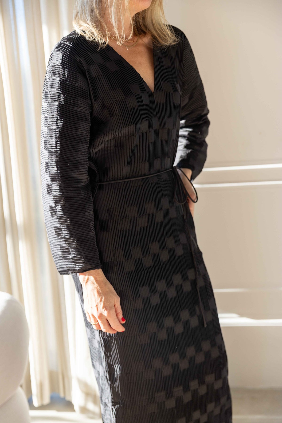 Close-up of the by Malene Birger Francis Dress in black pleated satin with V-neck and dolman sleeves