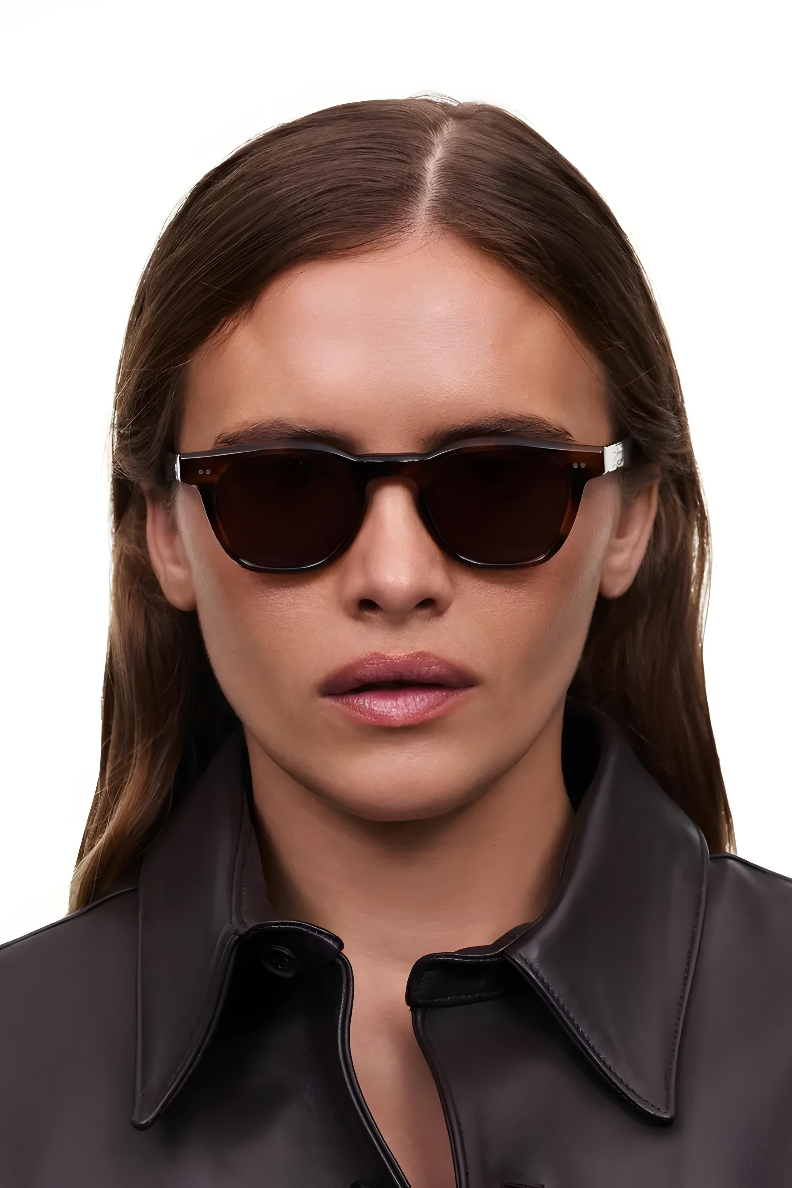 Woman wearing dark sunglasses with a plain background