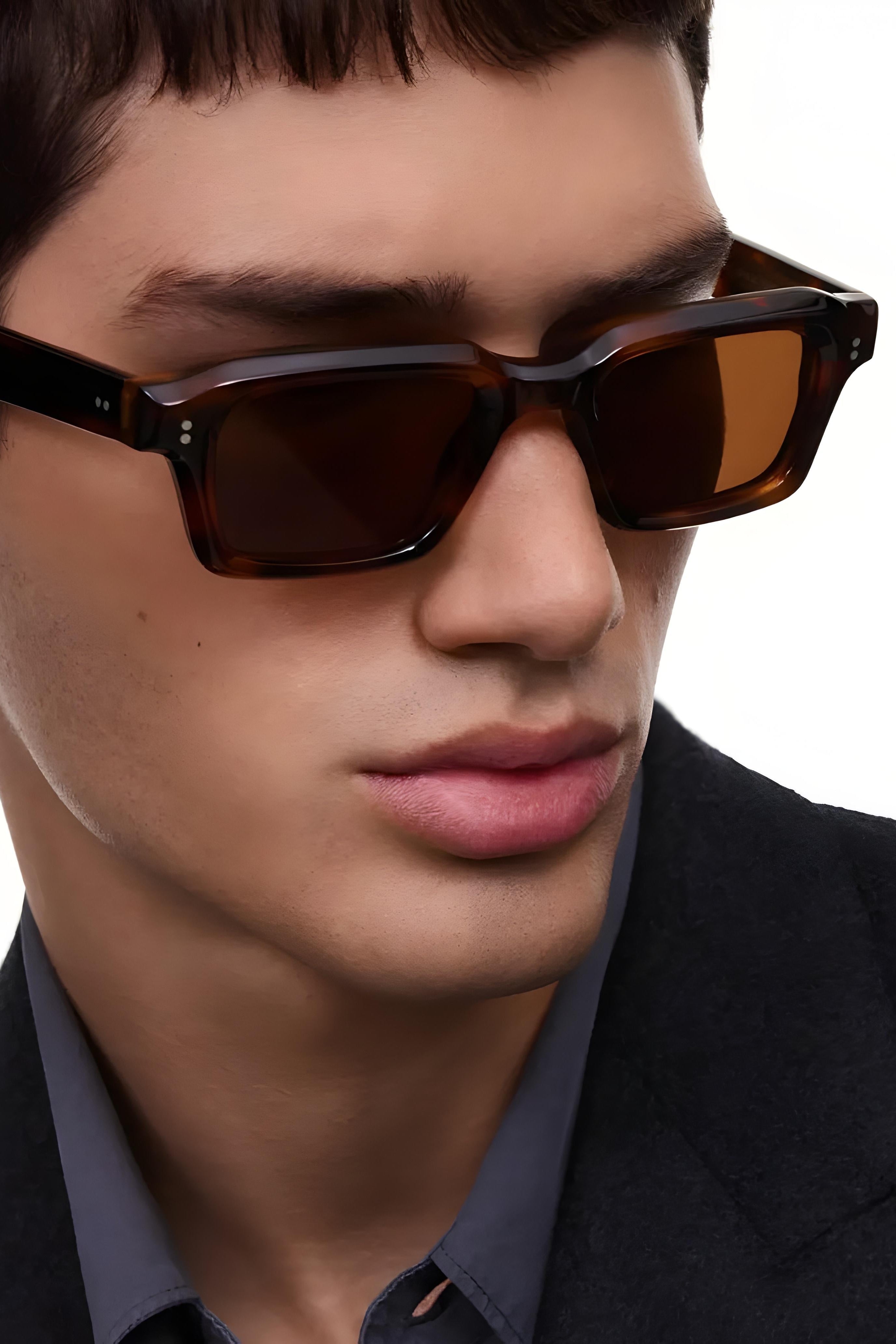 Close-up of a person wearing brown sunglasses with a neutral background