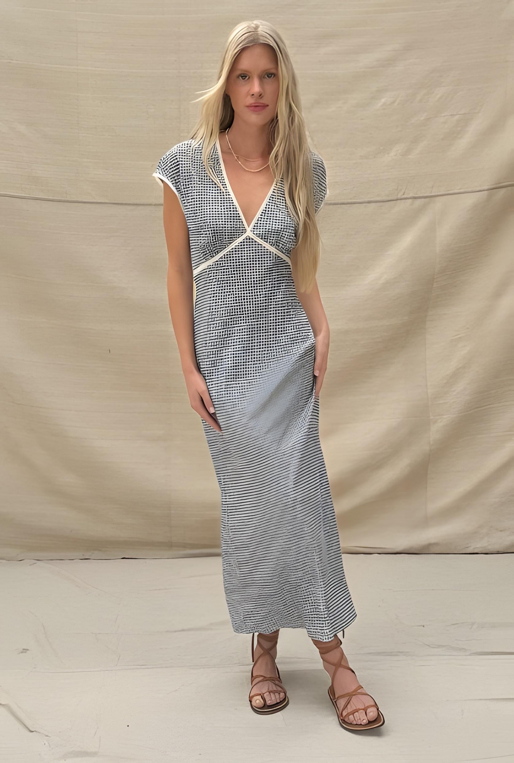Woman wearing a long, patterned dress against a plain background