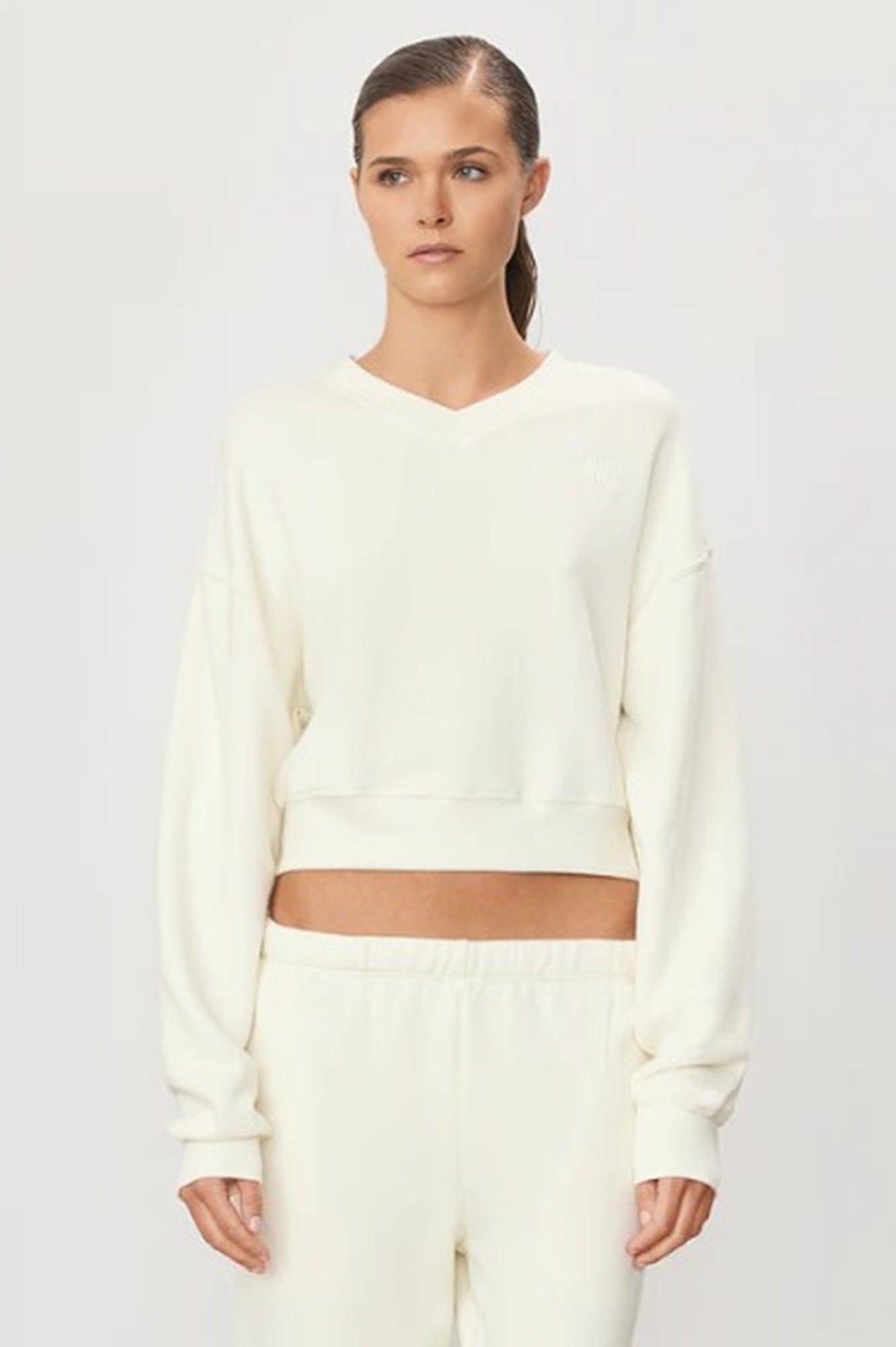 image of a model wearing the Eterne Cropped V Neck Sweatshirt in Cream
