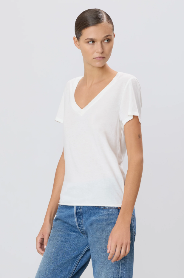 Woman wearing a white top and blue jeans against a plain background