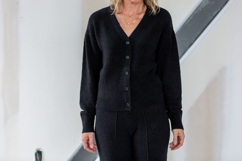 Person wearing a black cardigan and pants in an indoor setting