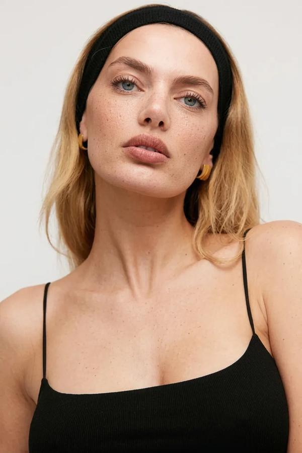 Woman wearing a black headband and black top against a white background