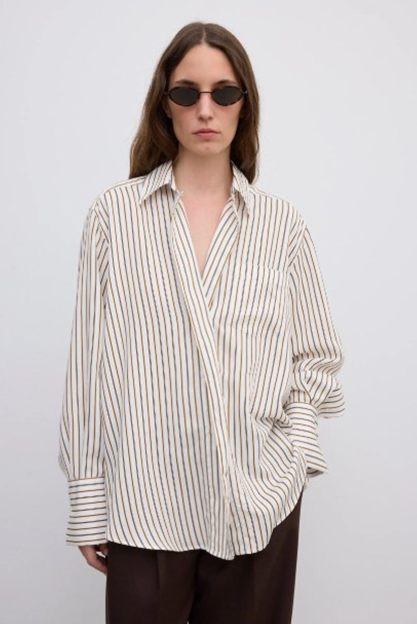 Person wearing a striped shirt and sunglasses on a plain background
