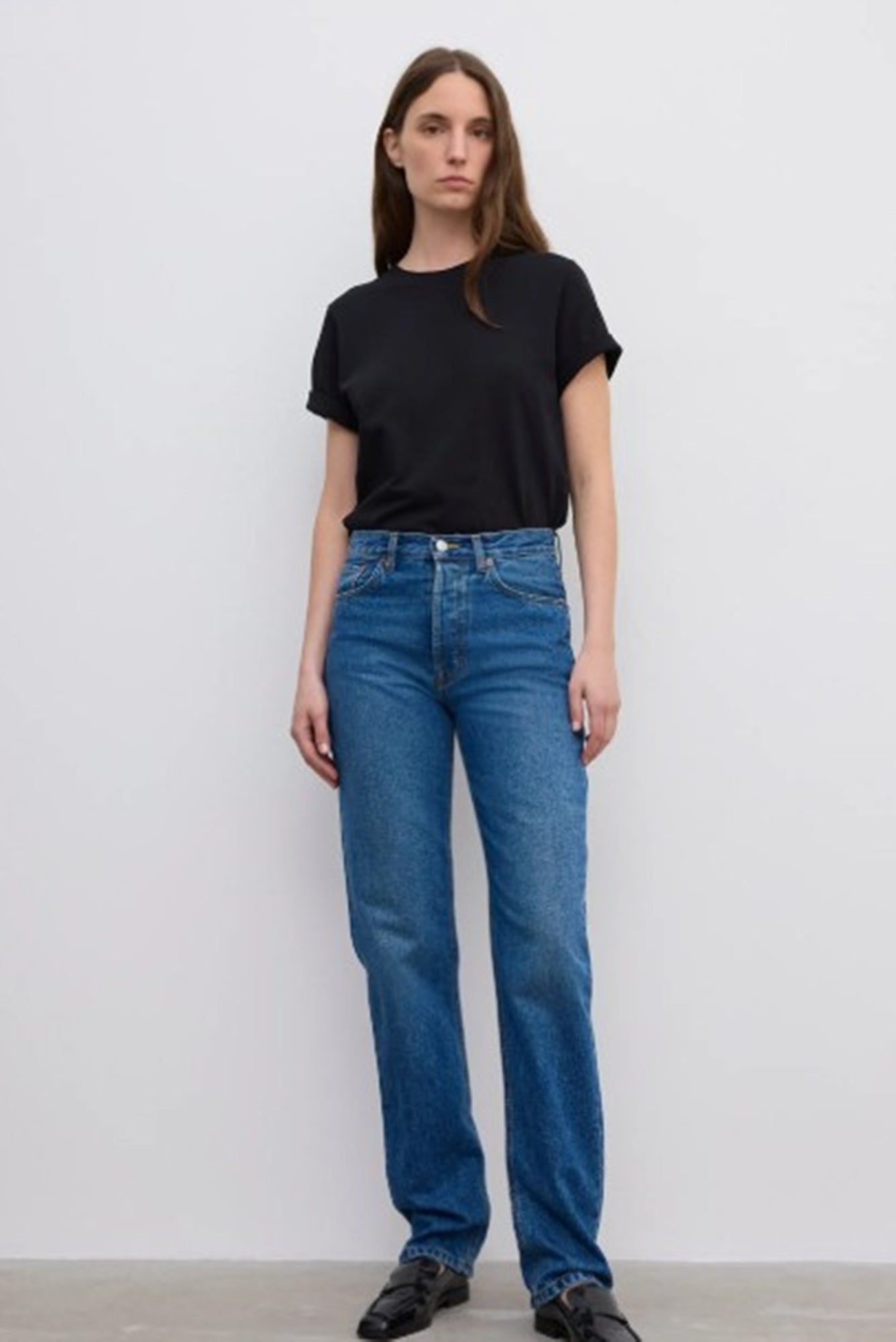 Person wearing a black t-shirt and blue jeans against a white background