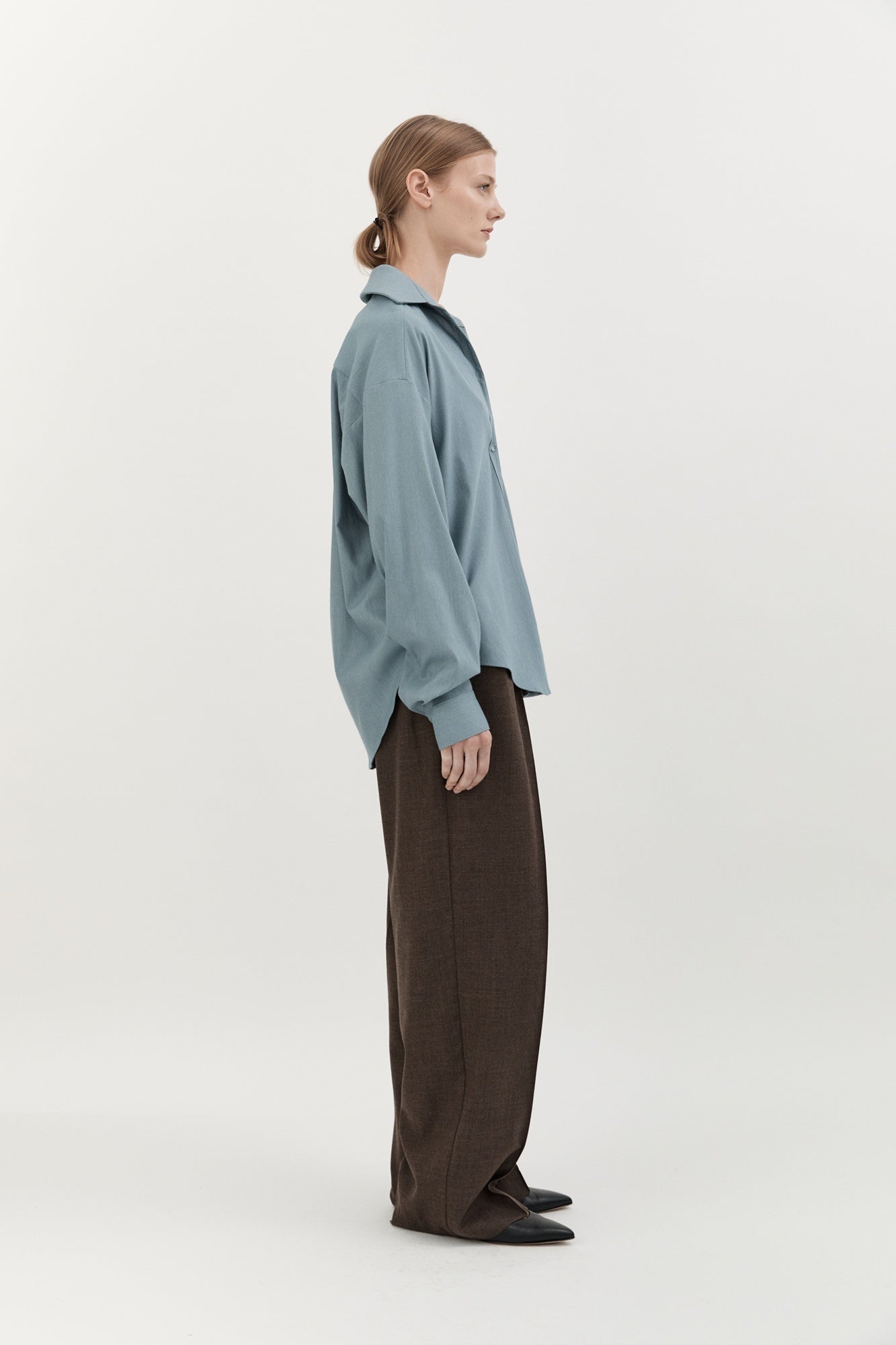 Person wearing a light blue sweater and brown pants on a white background