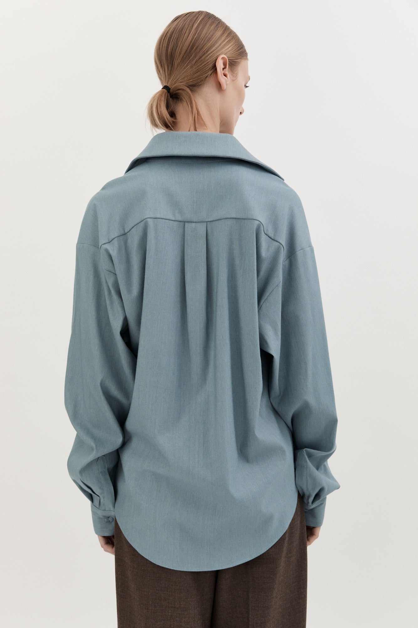 Person wearing a light blue shirt with a white background