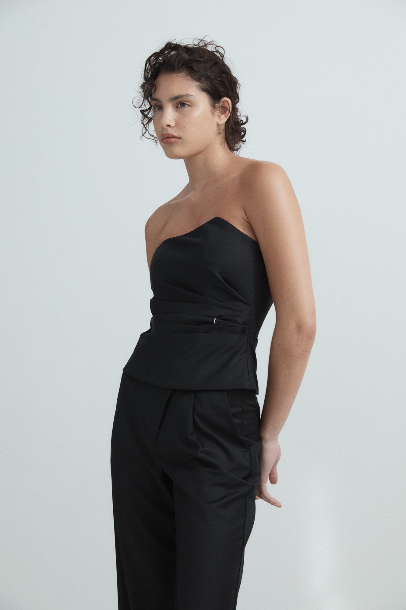 Woman wearing a black strapless top and black pants on a white background