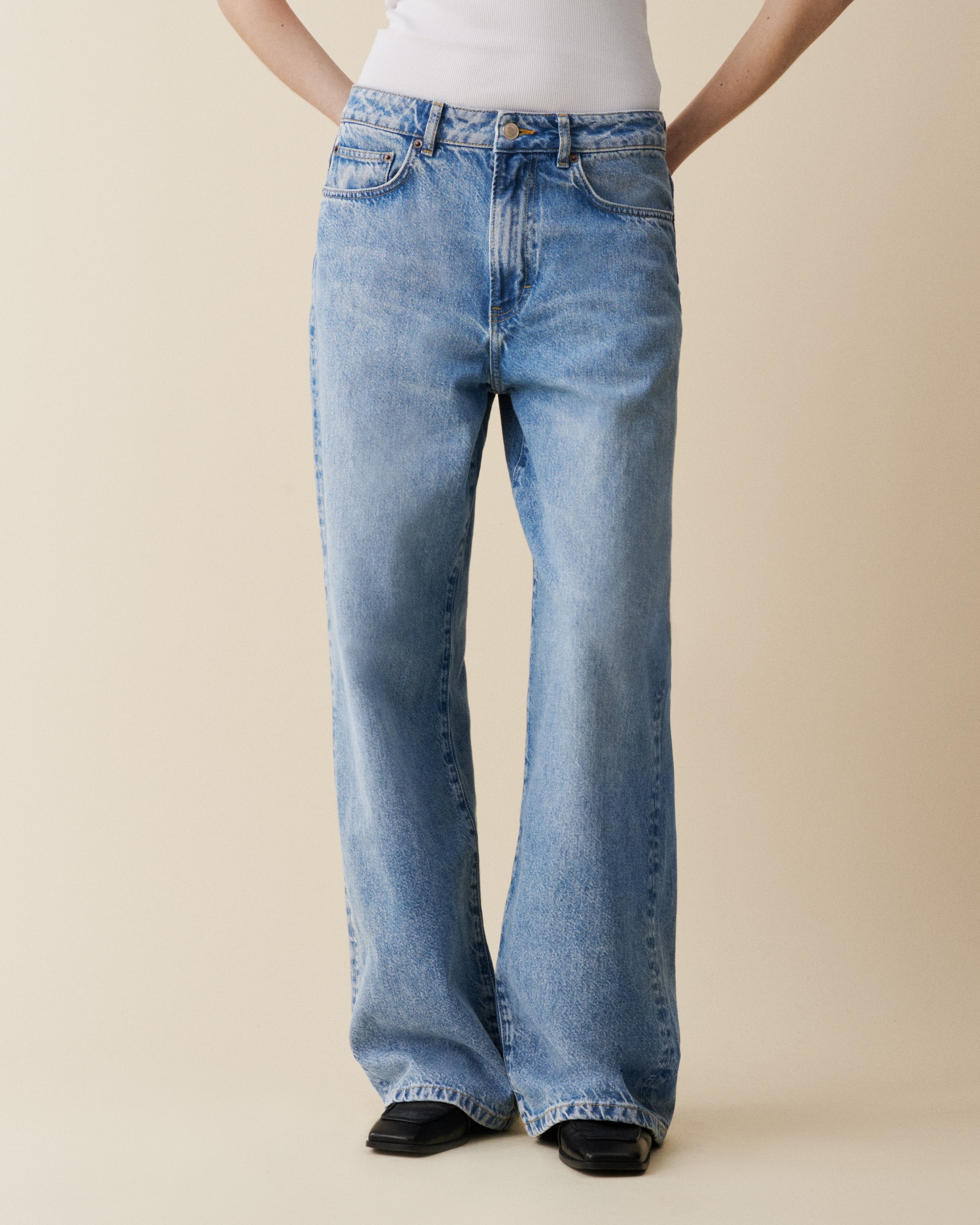 Person wearing blue jeans on a beige background