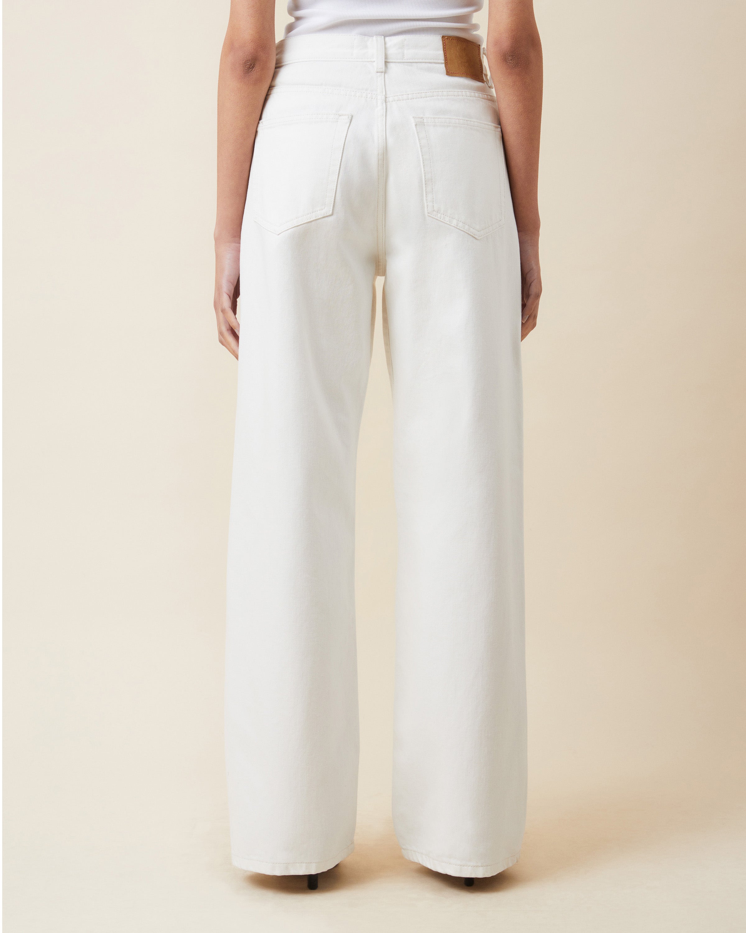 White wide-leg pants worn by a person on a beige background