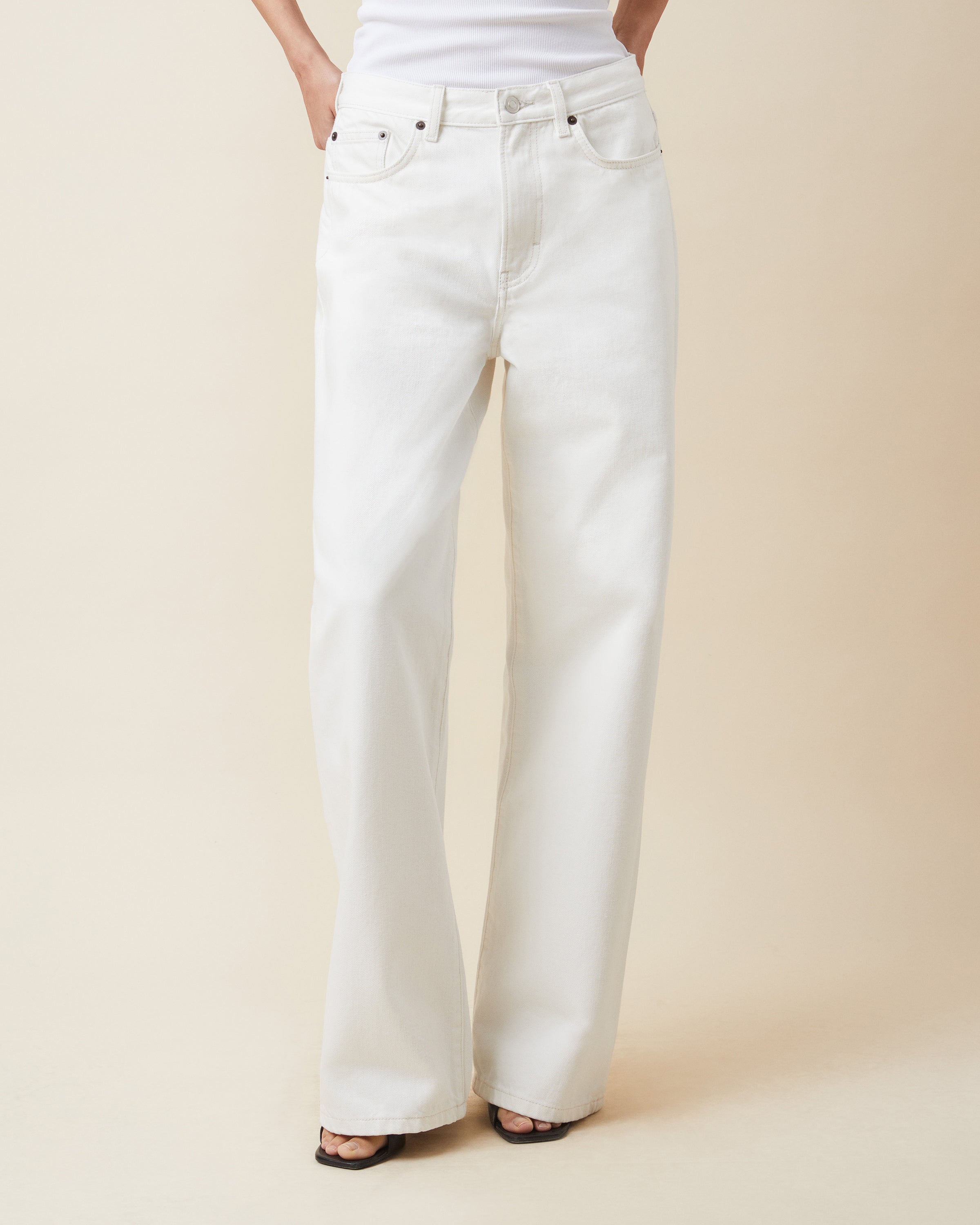 White jeans worn by a person on a beige background