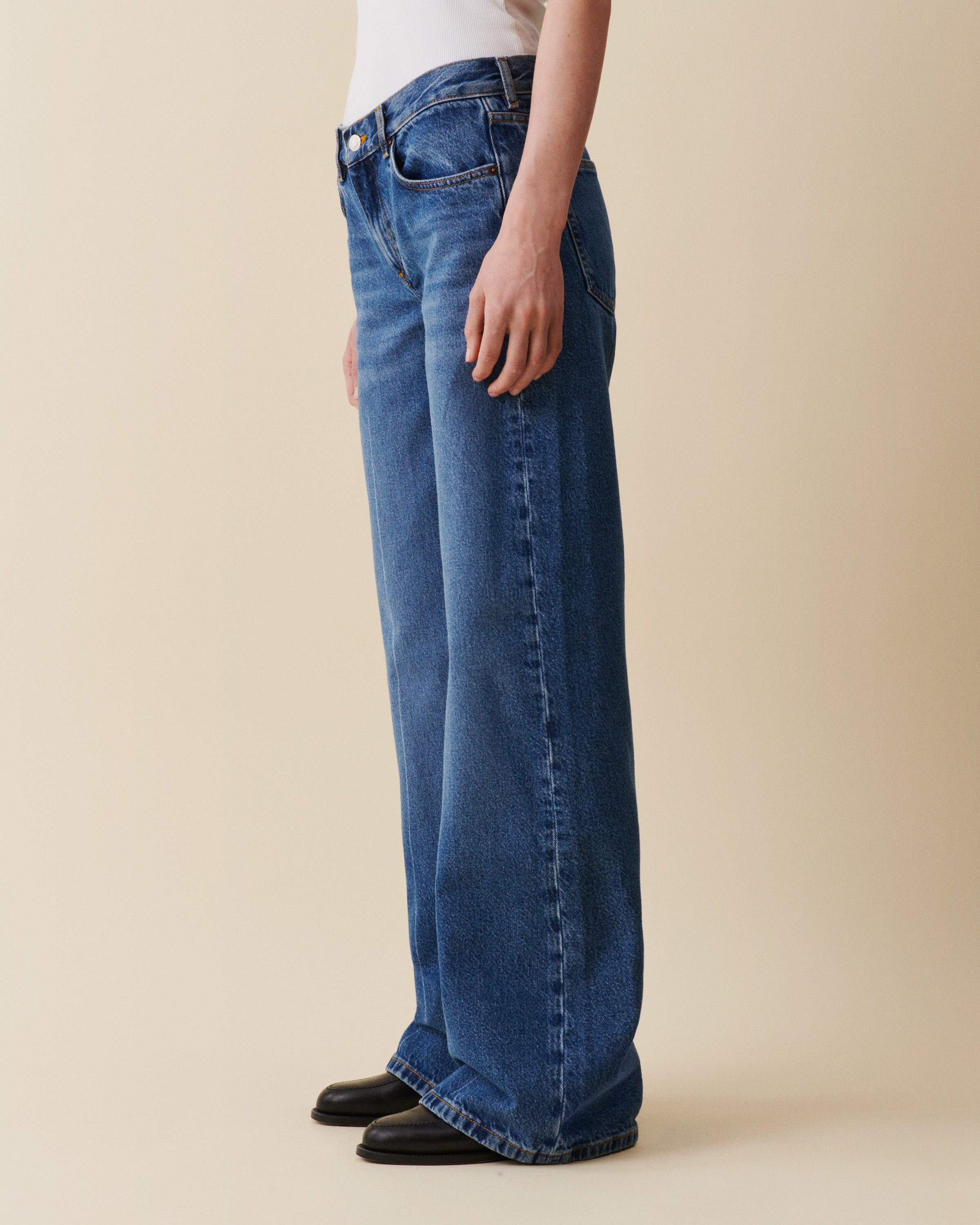 Person wearing blue jeans on a beige background