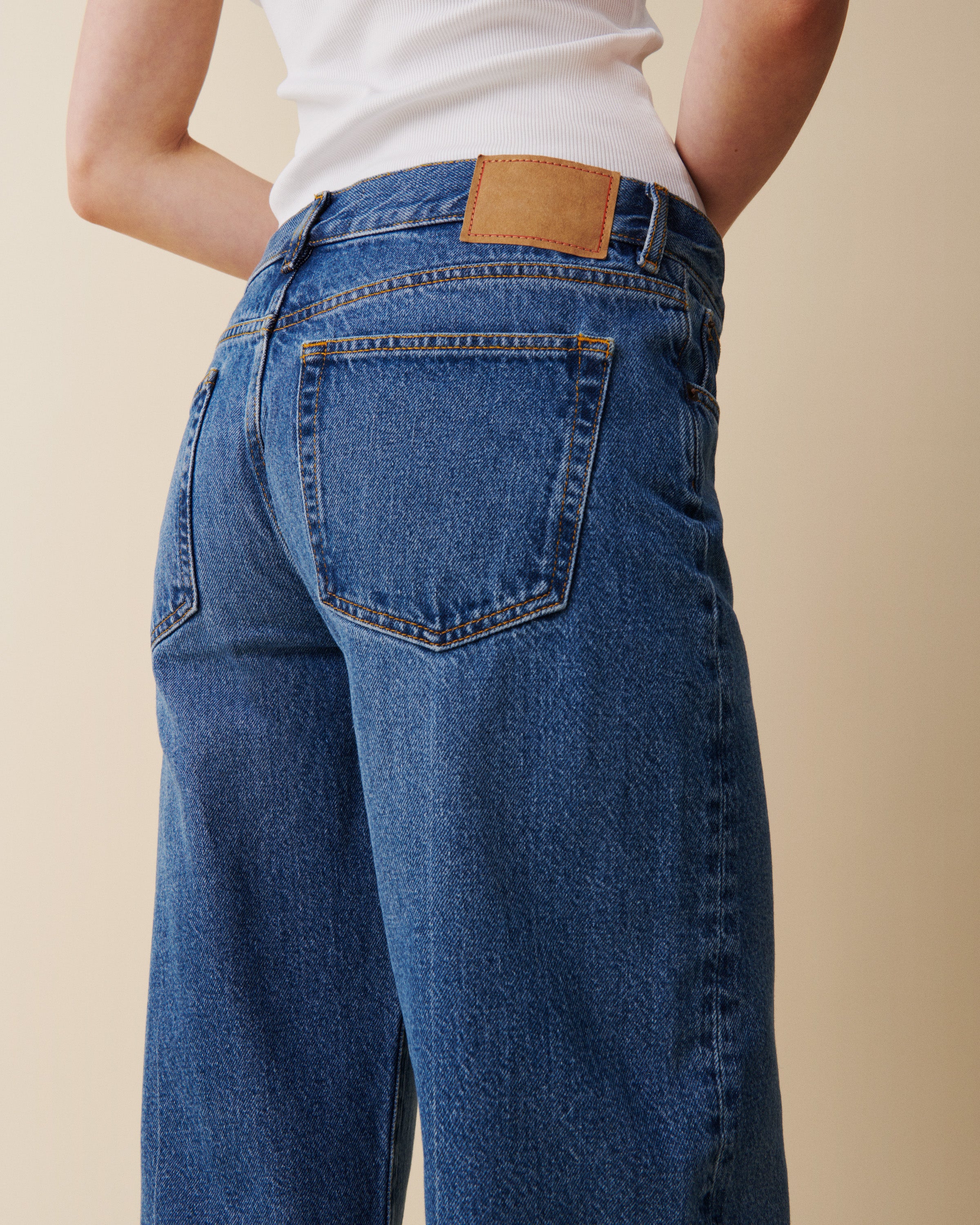 Person wearing blue jeans with a beige background