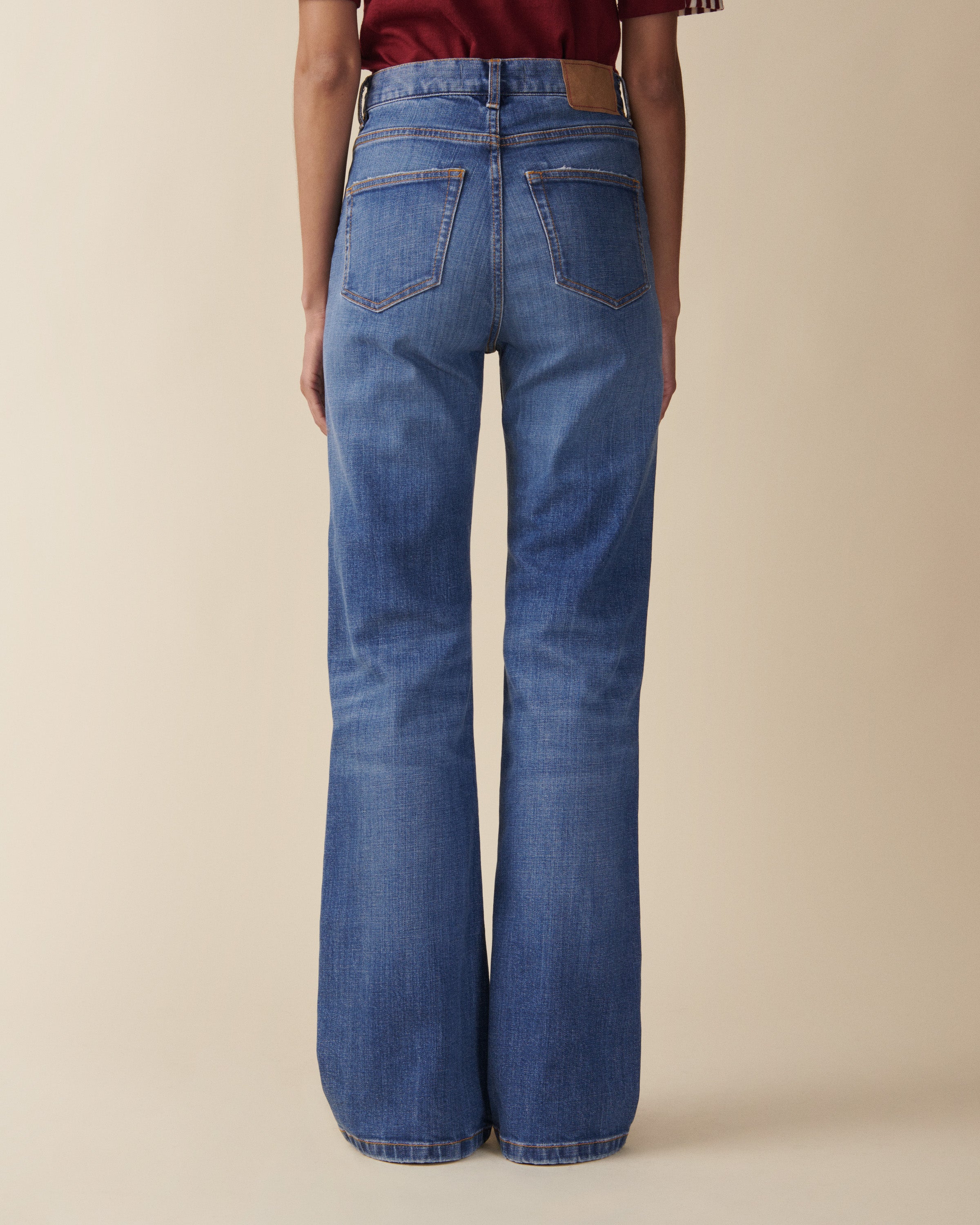 Blue jeans worn by a person on a beige background