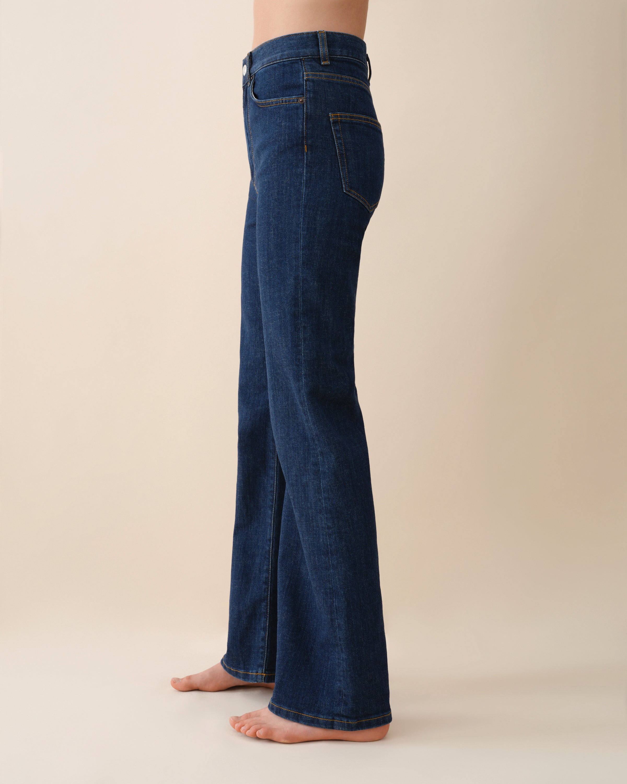 Dark blue flared jeans on a beige background