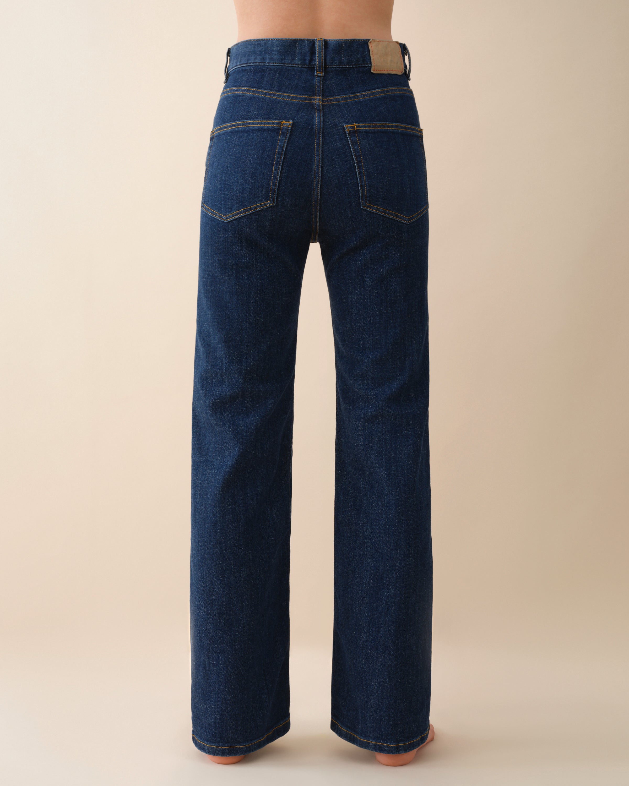 Blue jeans worn by a person on a beige background