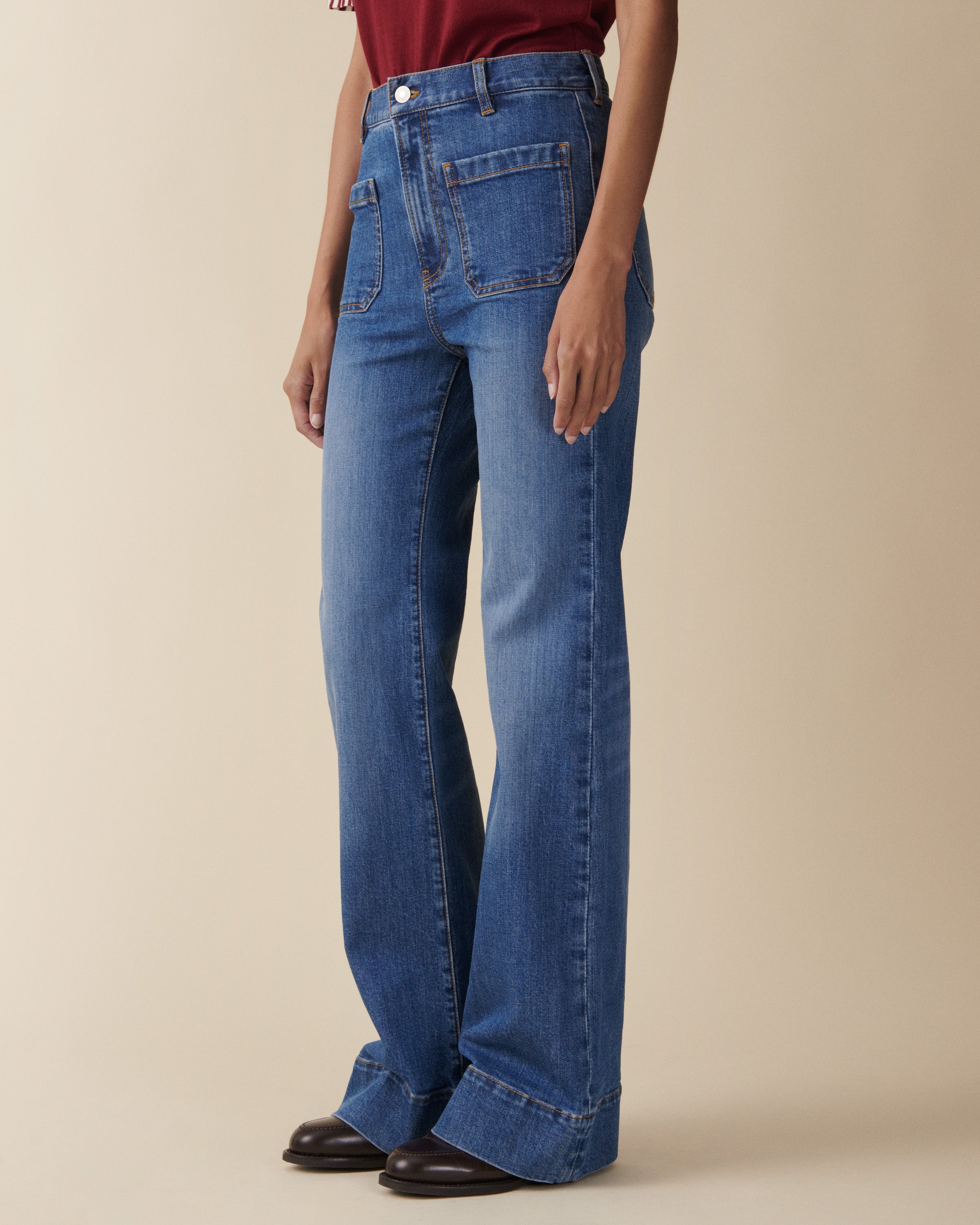 Person wearing blue jeans on a beige background