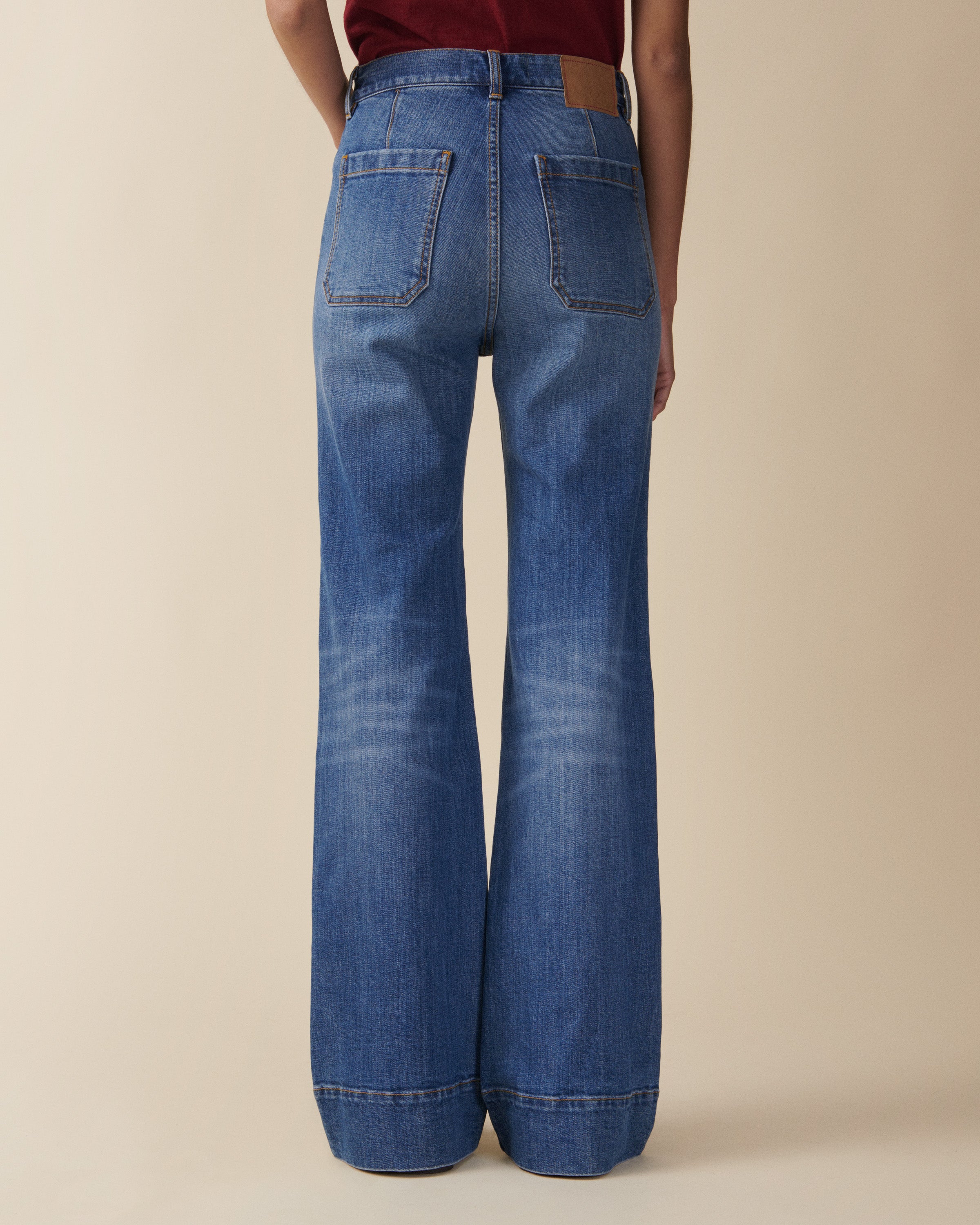 Blue jeans worn by a person on a beige background