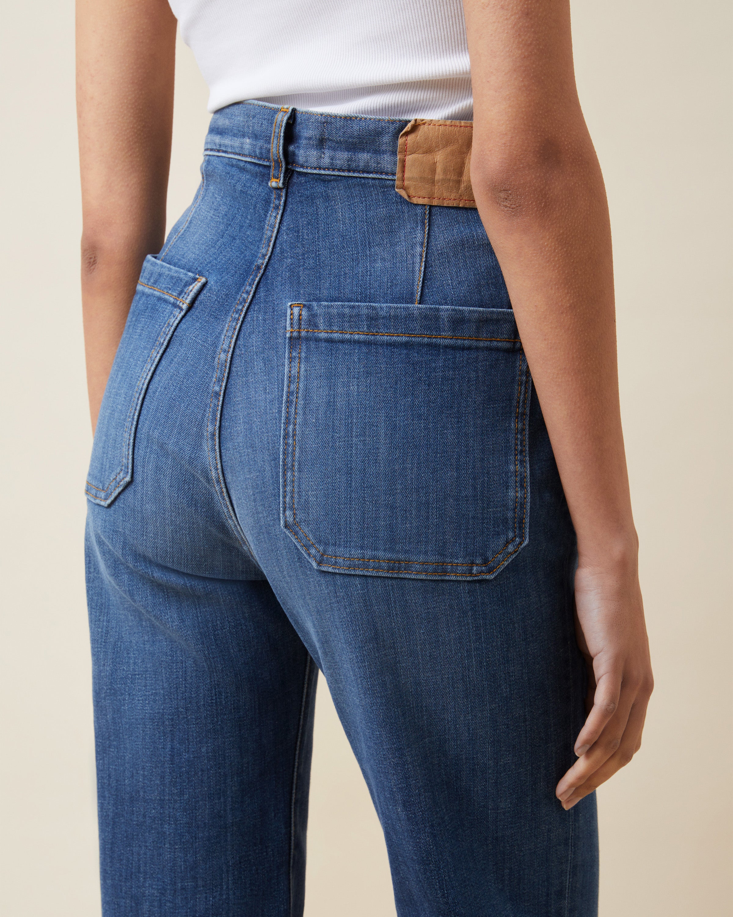 Person wearing blue jeans with a beige background