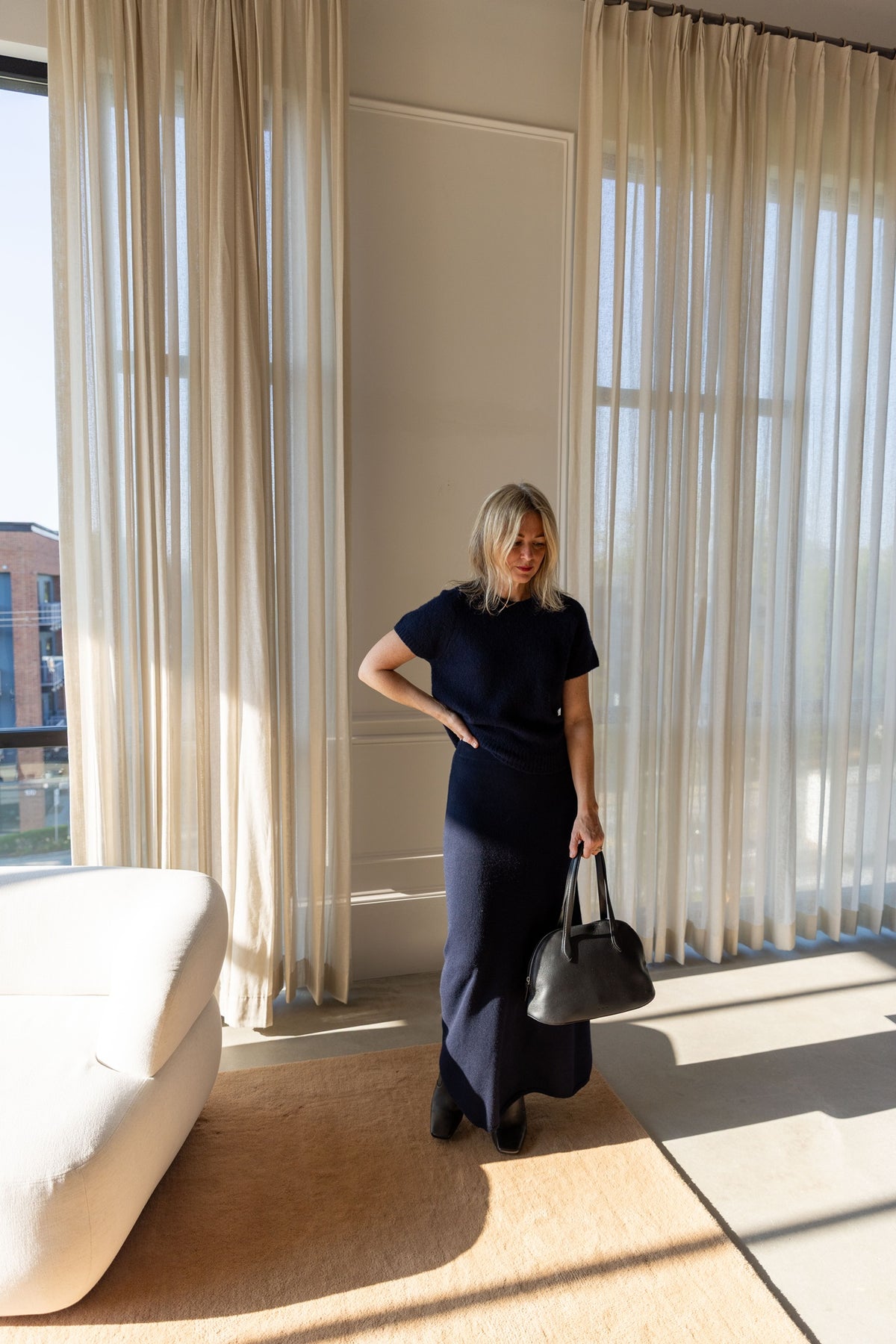 Lisa Yang Cila T-Shirt and Dolly Skirt in navy cashmere, full-length view with a black top-handle bag