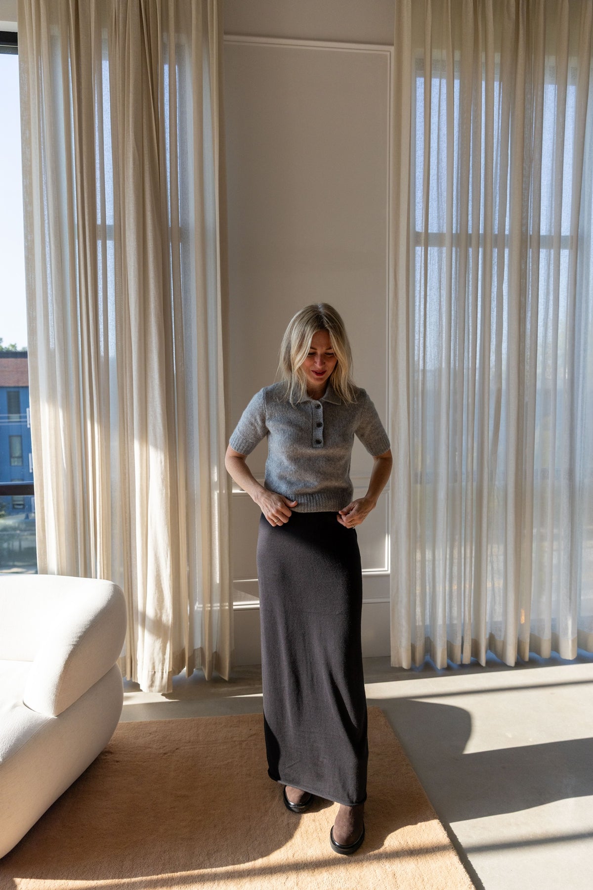 Lisa Yang Masy Sweater in cloudy grey with the Charlotta maxi skirt, full-length view in a sunlit room
