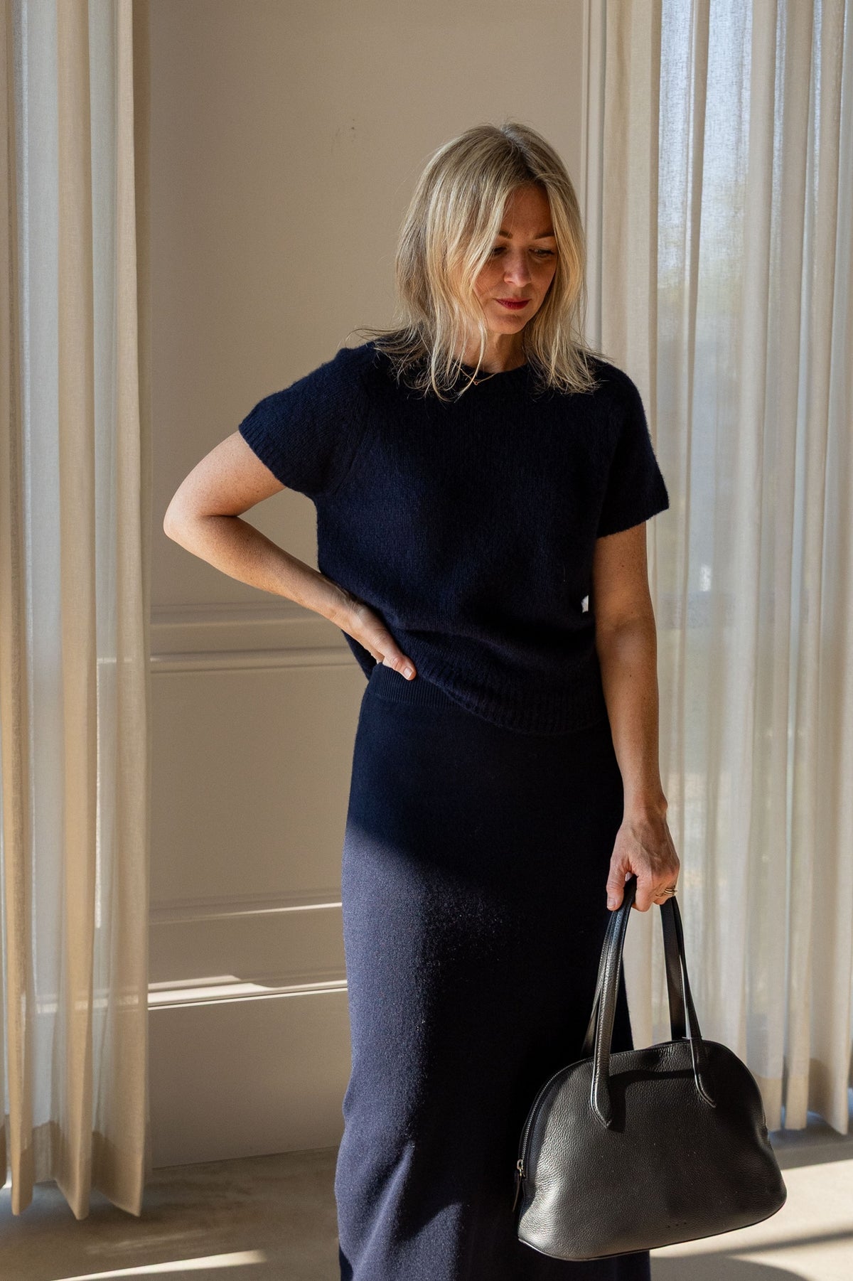 Lisa Yang Siona T-Shirt in navy silk cashmere styled with the navy Dolly Skirt and a grey top-handle bag