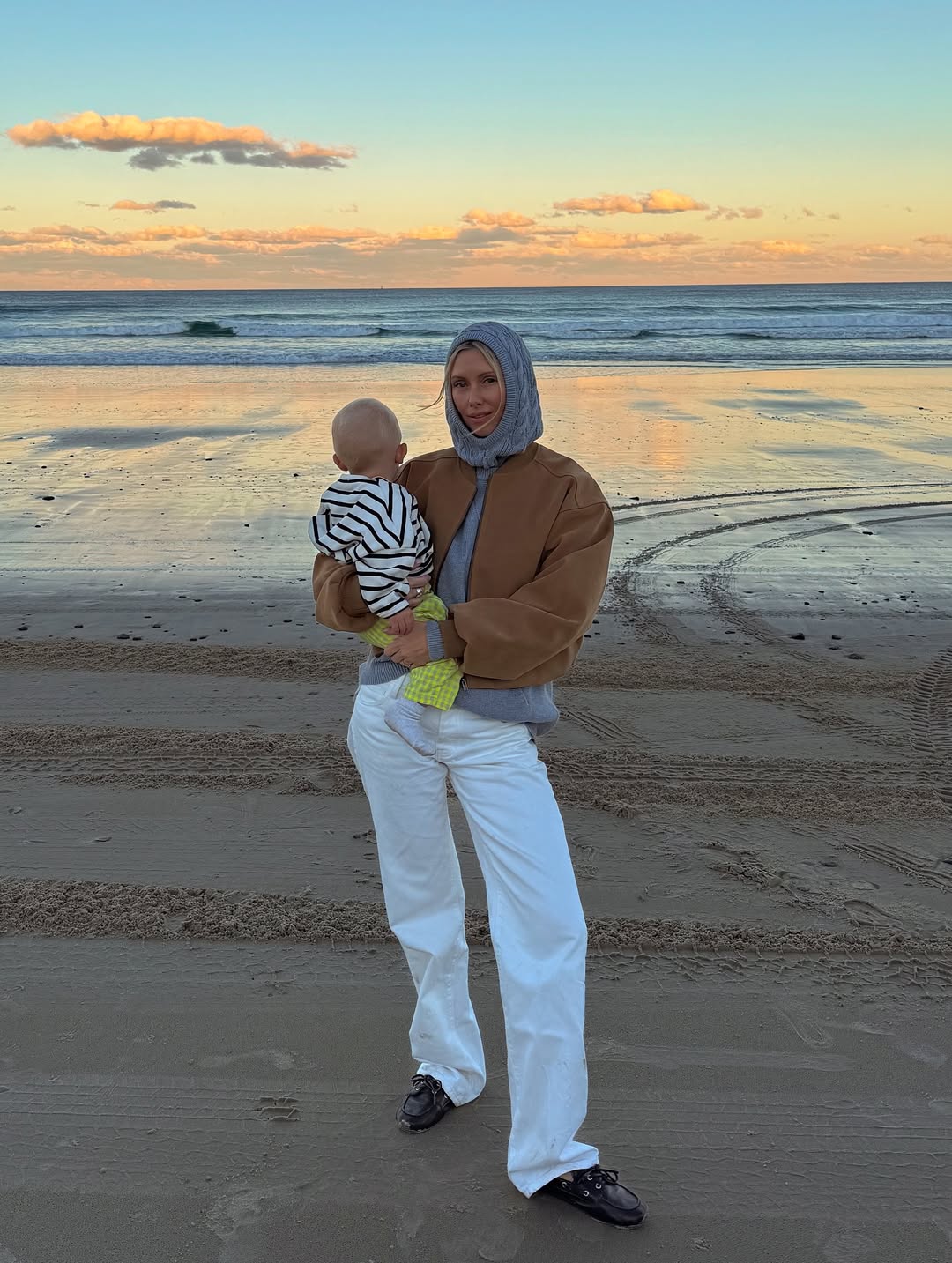 Woman holding a child on a beach at sunset