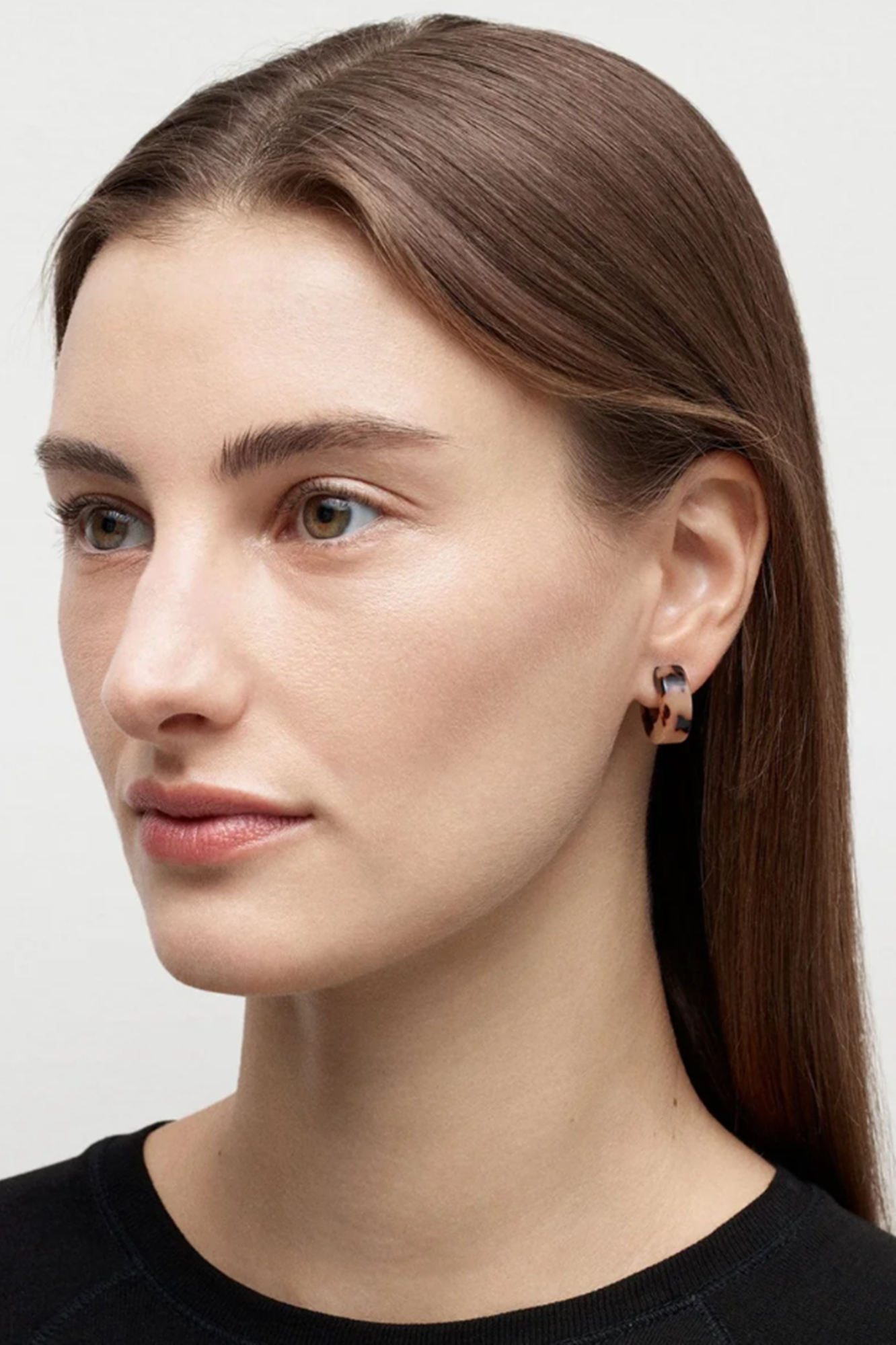 Close-up of a woman wearing earrings with a neutral background
